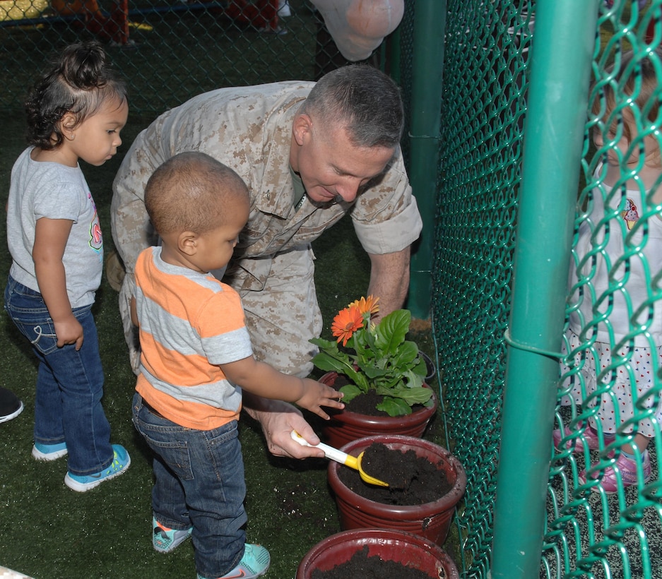 Col. Don Davis, commanding officer, Marine Corps Logistics Base Albany, plants flowers with children from the Child Development Center in recognition of Earth Day, April 22.