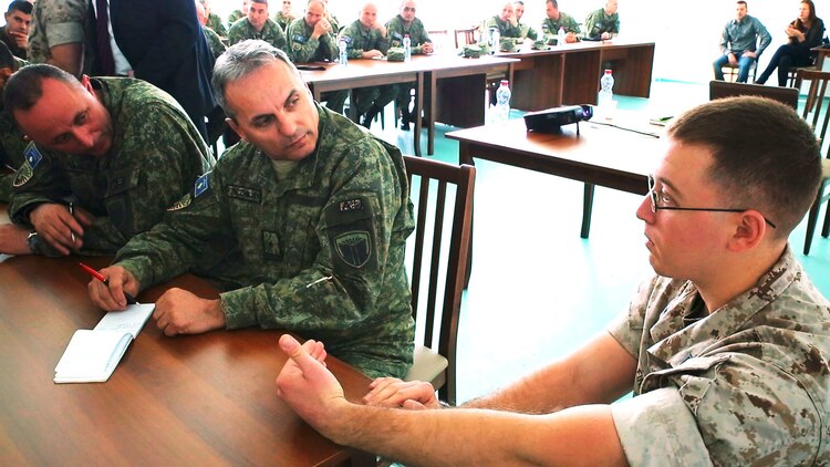 U.S. Marine Staff Sgt. Joseph Finn with Black Sea Rotational Force and Kosovo Security Force members discuss the responsibilities of the operations watch-stander in the combat operations center during a military-to-military engagement at Camp Adem Jashari in Pristina, Kosovo April 14-24, 2015. The command and control and combat operations center workshops ended with applying the information gained from the discussions into a practical application Command Post Exercise scenario.