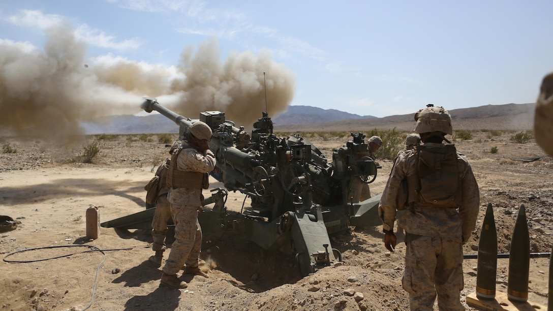 Corporal Osmar S. Gorish, a section chief for Battery A, 1st Battalion, 11th Marine Regiment, 1st Marine Division, observes a round being shot down range during Exercise Desert Scimitar 2015 aboard Marine Corps Air Ground Combat Center Twentynine Palms, Calif., April 20, 2015. The tough, realistic live-fire training central to Desert Scimitar allows Division units to train in order to maintain readiness and meet current and real-world operational demands.