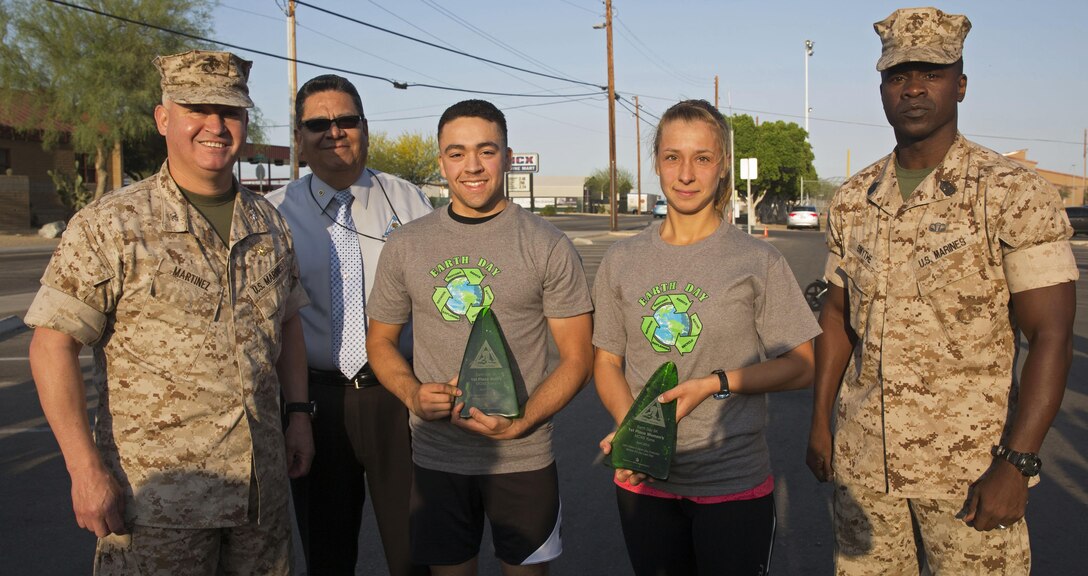 Col. Ricardo Martinez, the station commanding officer, David Rodriguez, the station environmental director, and Sgt. Maj. Delvin Smythe, the station sergeant major, present Lance Cpl. Alfilio Martinez, an aircraft electronic countermeasures systems technician with Marine Tactical Electronic Warfare Squadron 3 based out of Marine Corps Air Station Cherry Point, N.C., and Lucie Warren, a civilian member of the community, with awards for coming in first place in the men’s and women’s category of the Earth Day 5k run at Marine Corps Air Station Yuma, Ariz., Wednesday, April 22, 2015. 