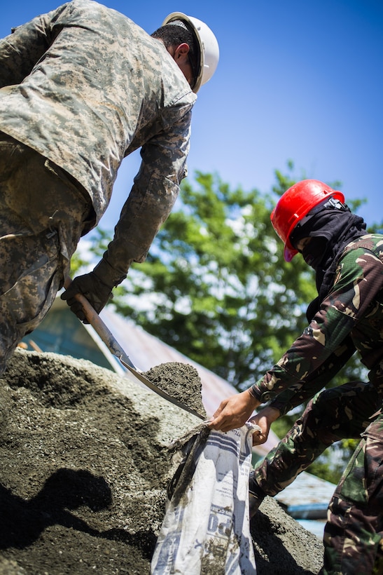 Philippine Army Pfc. Bernabe Tabot, right, with the 514th Engineer Construction Battalion, 51st Brigade, holds a bag while U.S. Army Pfc. Justin Negron, left, a plumber with the 643rd Engineer Company, 84th Engineer Battalion, 130th Engineer Brigade, shovels sand and rock for a classroom being built at the Sabang Elementary School in Sabang, Philippines, during exercise Balikatan 2015, April 21. This year marks the 31st iteration of the exercise, which is an annual Philippines-U.S. bilateral military training exercise and humanitarian civic assistance engagement.