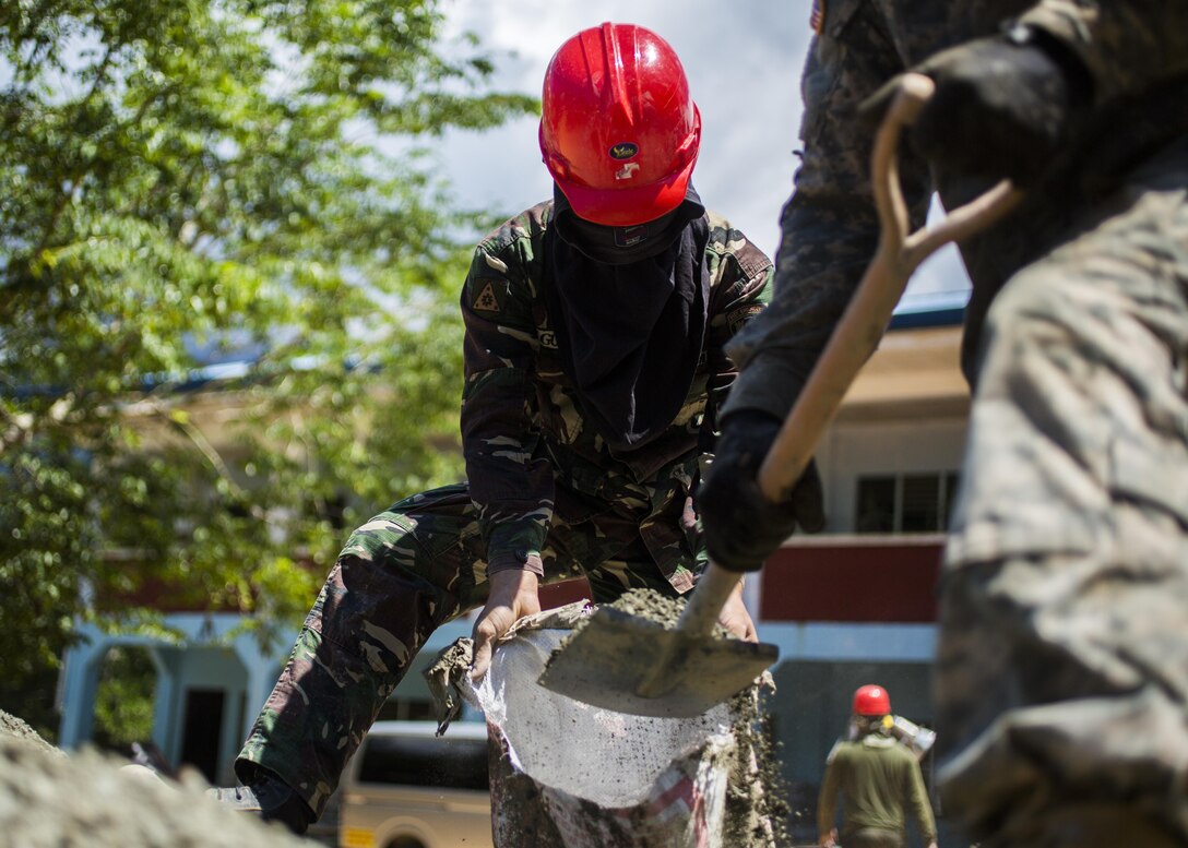 Philippine Army Pfc. Bernabe Tabot, left, 514th Engineer Construction Battalion, 51st Brigade, holds a bag while U.S. Army Pfc. Justin Negron, right, a plumber with the 643rd Engineer Company, 84th Engineer Battalion, 130th Engineer Brigade, shovels sand and rock for a classroom being built at the Sabang Elementary School in Sabang, Philippines, as part of humanitarian civic assistance projects during exercise Balikatan 2015, April 21. This year marks the 31st iteration of the exercise, which is an annual Philippines-U.S. bilateral military training exercise and humanitarian civic assistance engagement.