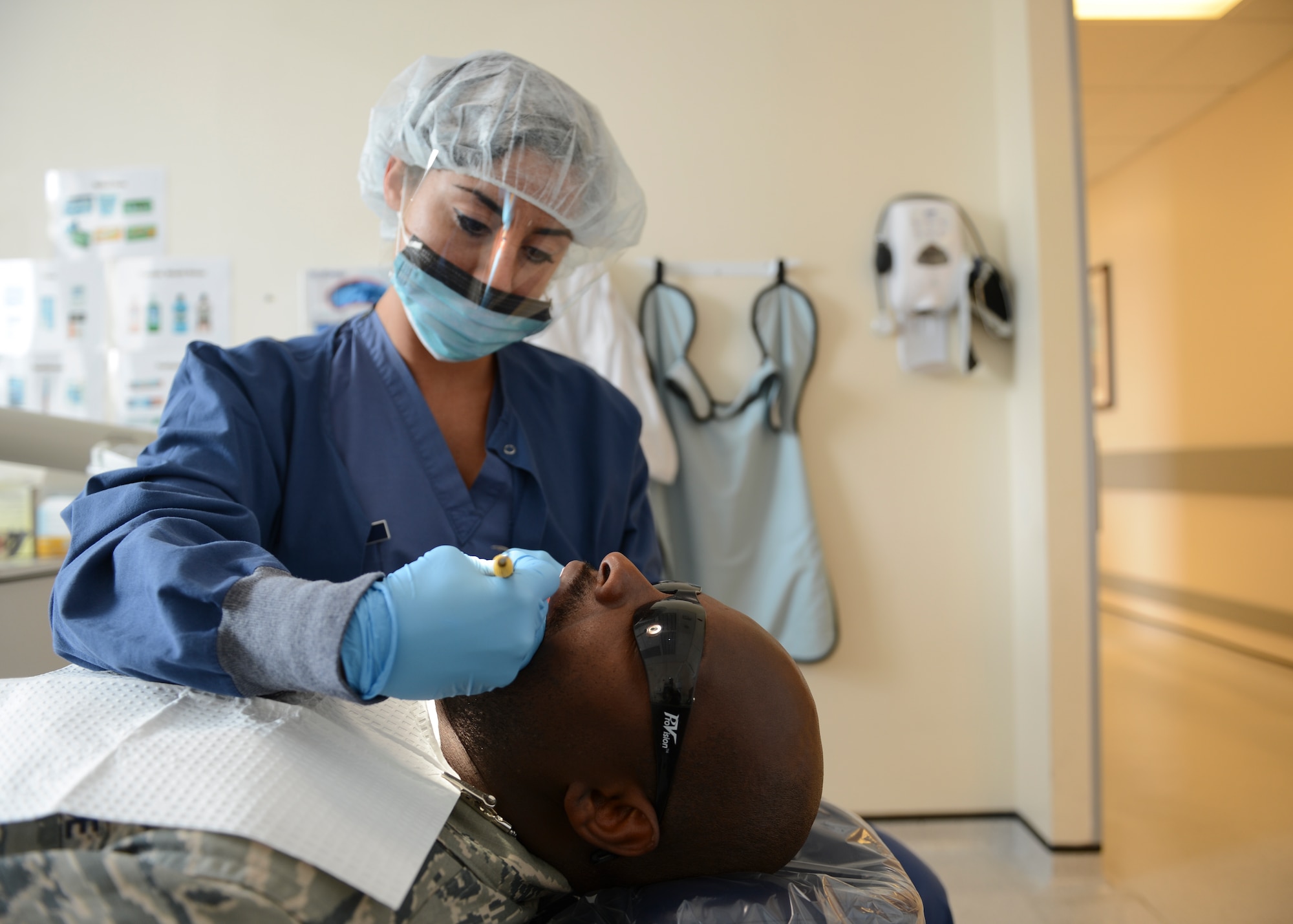 Staff Sgt. Alysia Macedo, 48th Dental Squadron dental hygienist, performs a teeth-scraping procedure on Tech. Sgt. Mohamed Swarray, 48th Surgical Operations Squadron NCO in charge of x-ray quality control, at Royal Air Force Lakenheath, England, April 17, 2015. Macedo’s dedication to personal fitness earned her success at the recent Fitness Helsinki competition. (U.S. Air Force photo by Senior Airman Nigel Sandridge/Released)
