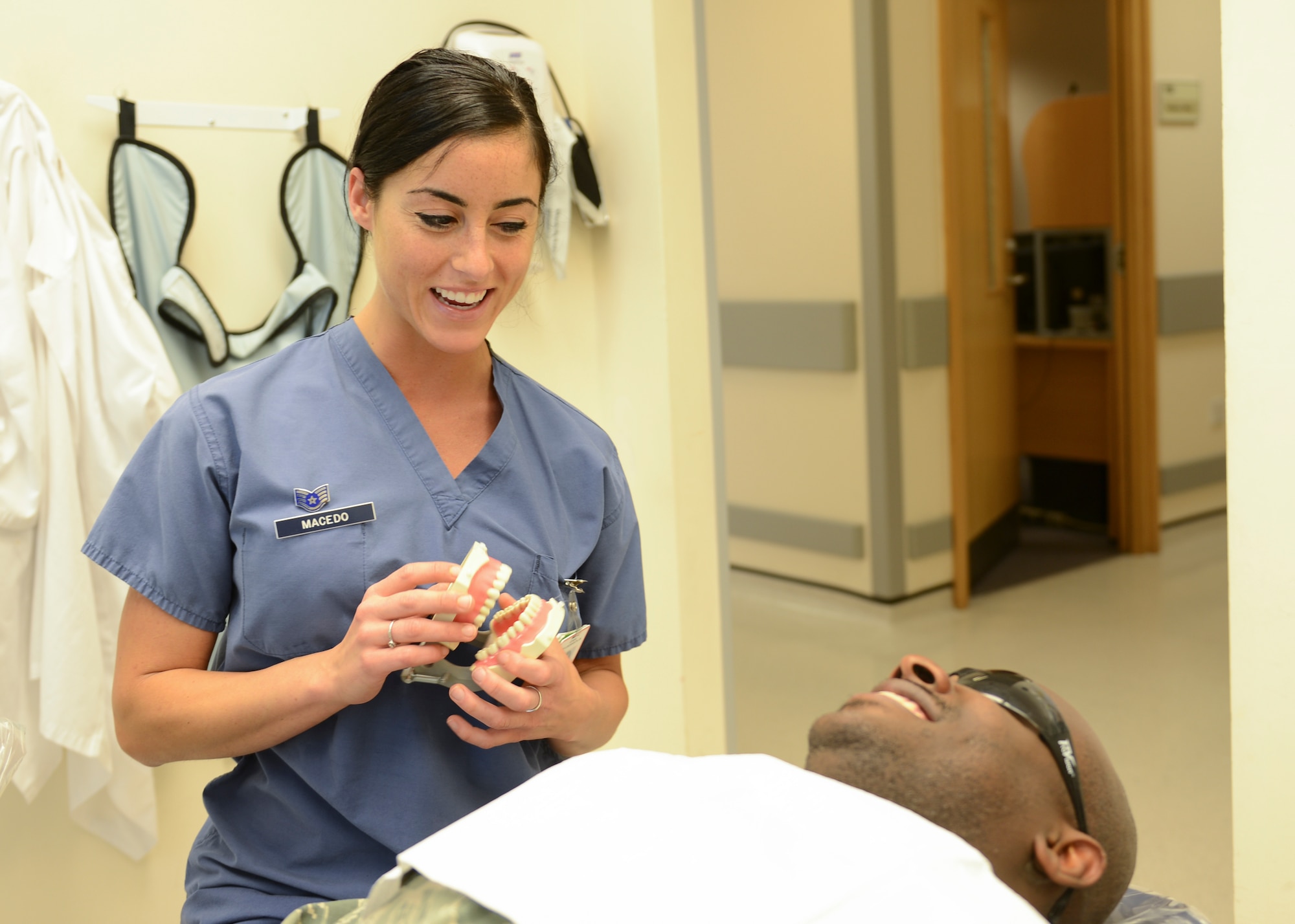 Staff Sgt. Alysia Macedo, 48th Dental Squadron dental hygienist, briefs Tech. Sgt. Mohamed Swarray, 48th Surgical Operations Squadron NCO in charge of x-ray quality control, on the dental cleaning procedure at Royal Air Force Lakenheath, England, April 17, 2015. Macedo’s dedication to personal fitness earned her success at the recent Fitness Helsinki competition. (U.S. Air Force photo by Senior Airman Nigel Sandridge/Released)