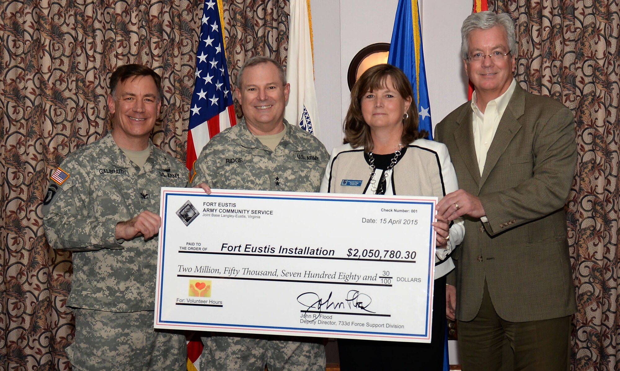U.S. Army Col. William Galbraith, 733rd Mission Support Group commander and Maj. Gen. Ross Ridge, Initial Military Training deputy commanding general, present a check to representing money saved to Donna Cloy, Army Community Service Army Community Corps coordinator, and John Flood, 633rd Force Support Squadron deputy director, during a ceremony at Fort Eustis, Va., April 15, 2015. Fort Eustis community members volunteered more than 81,000 hours over the past year. (U.S. Air Force photo by Staff Sgt. Teresa J. Cleveland/Released)