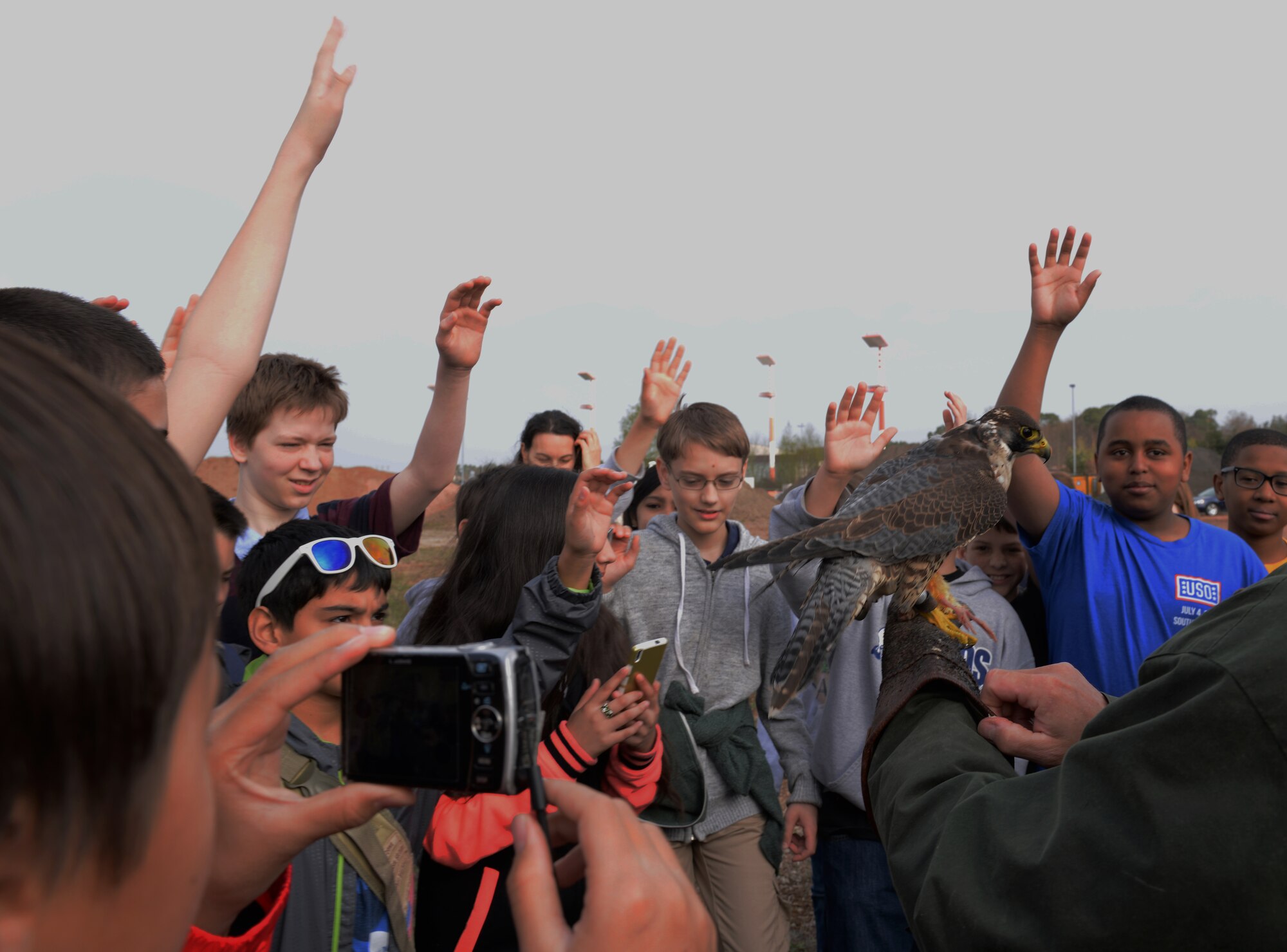 Sixth-grade students from Ramstein Middle School raise their hands to ask questions about peregrine falcons during the Bird Aircraft Strike Hazard demonstration presented to them for Earth Day April 16, 2015, at Ramstein Air Base, Germany. Some of the questions asked were where the falcons live, what they eat and if they had names. (U.S. Air Force photo/Airman 1st Class Tryphena Mayhugh)