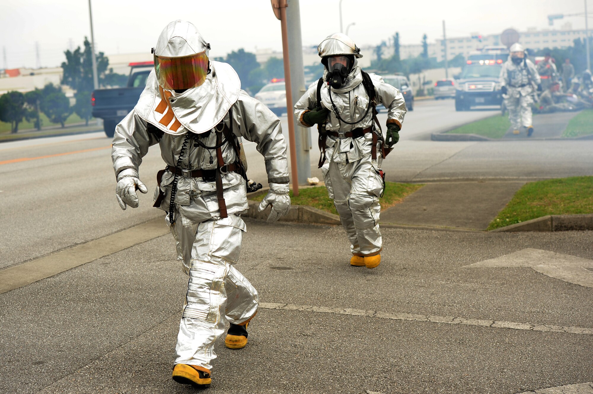 Two 18th Civil Engineer Squadron firefighters rush back to the scene of a simulated vehicle accident after moving simulated injured personnel to a safe location on Kadena Air Base, Japan, April 21, 2015. The scenario involved a chemical transportation truck becoming involved in a car accident, injuring personnel in the vehicle and dousing them with chemicals. The scenario was designed to test the response time, knowledge of procedures and interoperability of the 18th Wing’s first responders. (U.S. Air Force photo by Airman 1st Class Zade C. Vadnais)