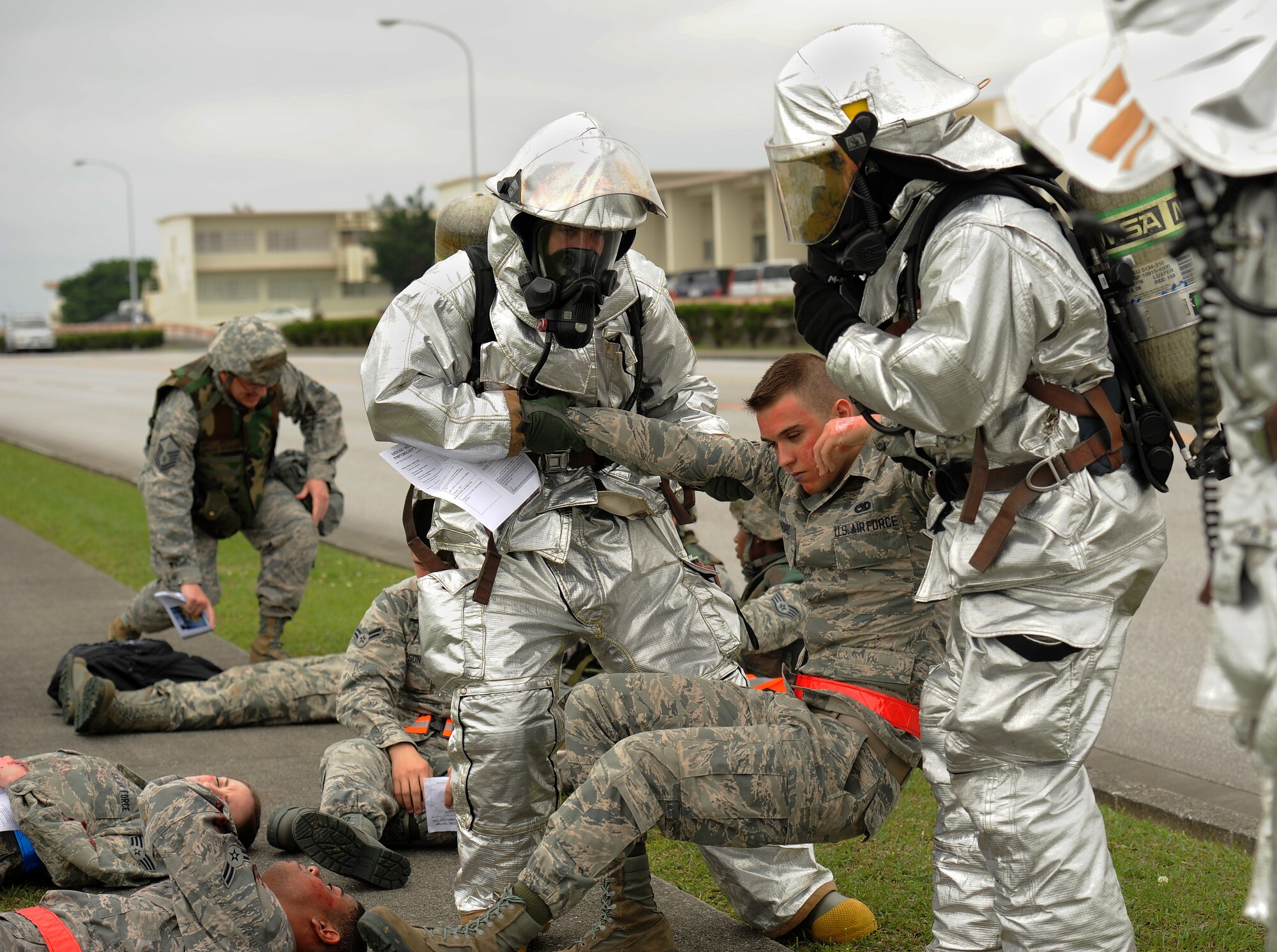 U.S. Air Force Airman Jack Spadaro, 18th Aircraft Maintenance Squadron aerospace propulsion specialist, is helped to his feet by two 18th Civil Engineer Squadron firefighters following a simulated vehicle accident on Kadena Air Base, Japan, April 21, 2015. Spadaro, along with other Airmen from units around the base, pretended to be a victim of a chemical transportation vehicle accident in order to test first responders’ reaction time and knowledge of self-aid buddy care procedures. (U.S. Air Force photo by Airman 1st Class Zade C. Vadnais)