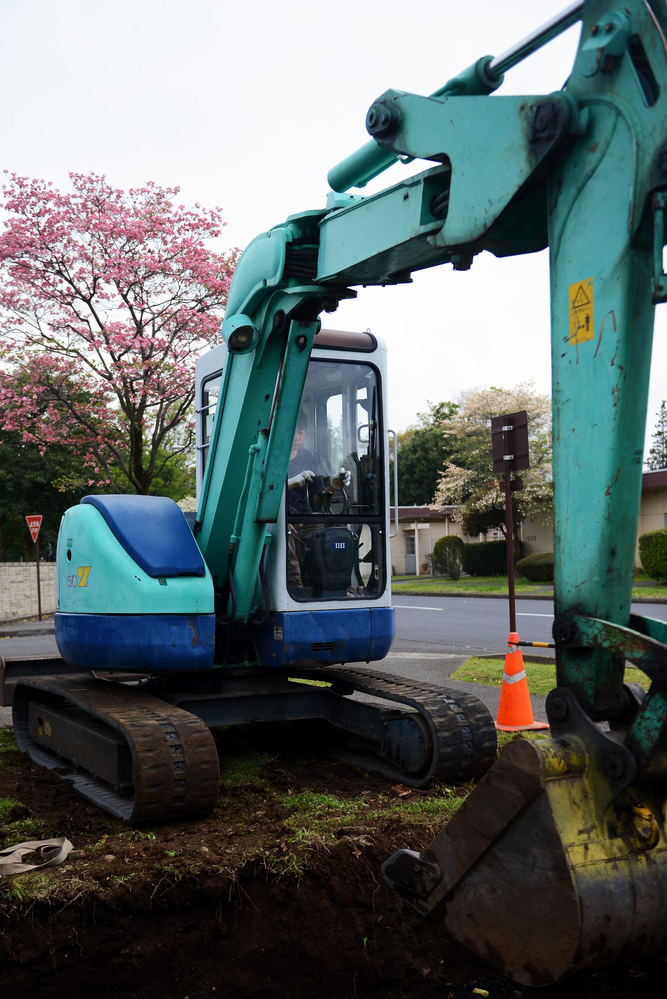 A Japanese civilian operates an excavator April 21, 2015 at Yokota Air Base, Japan. Working with 374th Civil Engineer Squadron Heating Ventilation and Air Conditioning Airmen, the excavator operator helped prepare a wall for installation. (U.S. Air Force photo by Airman 1st Class Delano Scott/Released)
