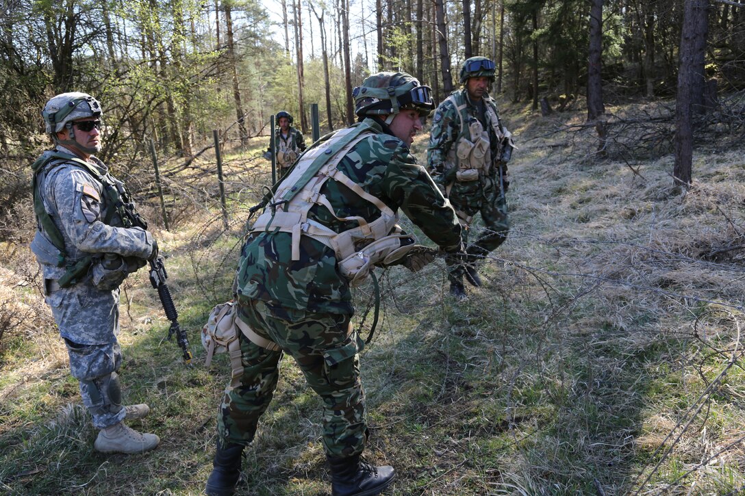 U.S. Army Staff Sgt. Thomas Raab, left, oversees the Bulgarian soldiers of Engineer Platoon as they construct a wire obstacle during exercise Saber Junction 15 at the U.S. Army’s Joint Multinational Readiness Center in Hohenfels, Germany, April 21, 2015. 