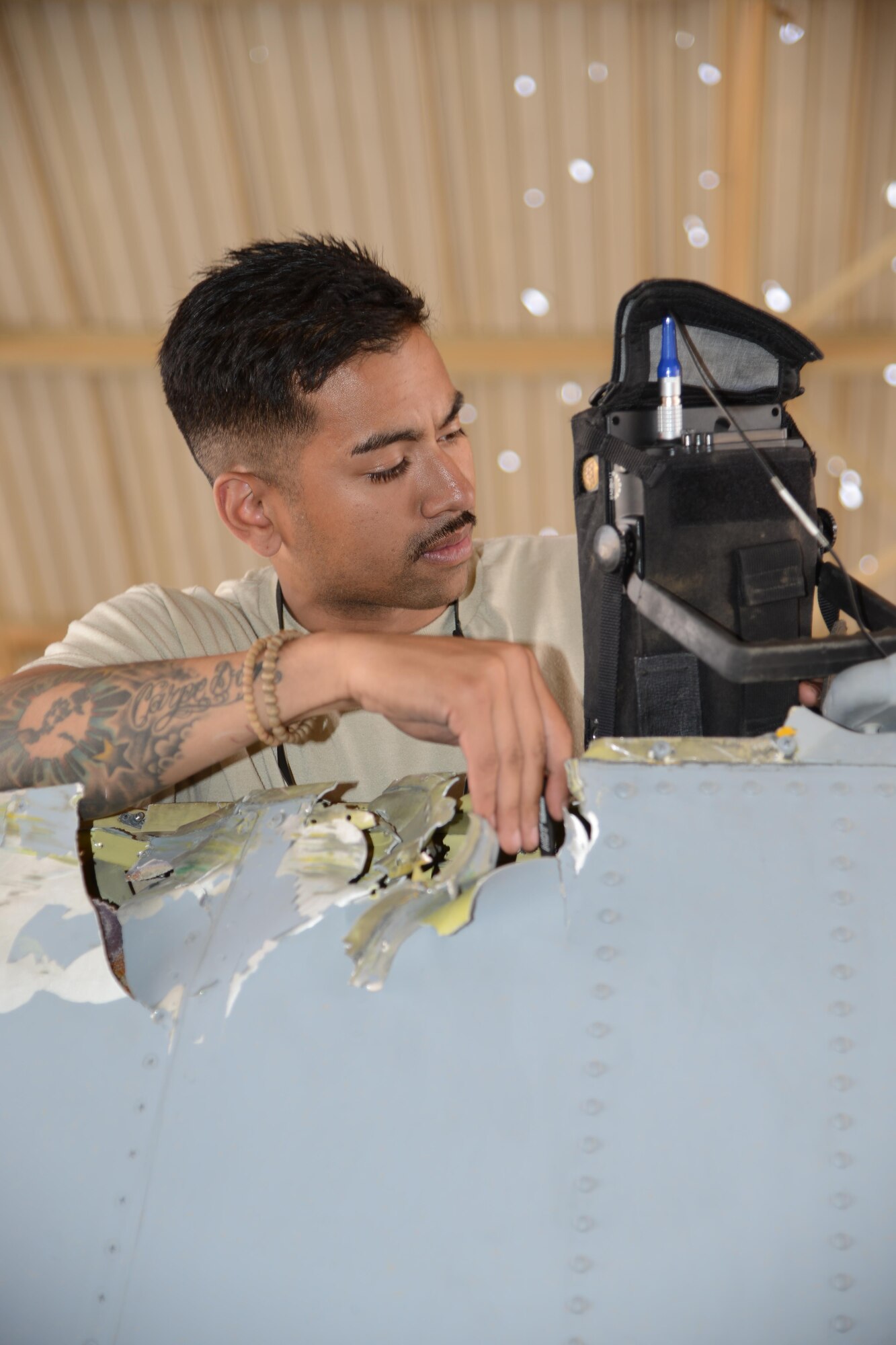 An Airman with the 332nd Expeditionary Maintenance Group perform a non-destructive inspection on a damaged verticle stabilizer from an A-10C Thunderbolt II at Al Asad Air Base, Iraq. A maintenance response team from the 332nd EMXG repaired the jet and got it back in the air less than five days after the jet suffered catastrophic engine failure and had to divert there. (U.S. Air Force photo by Tech. Sgt. Jared Marquis/released)