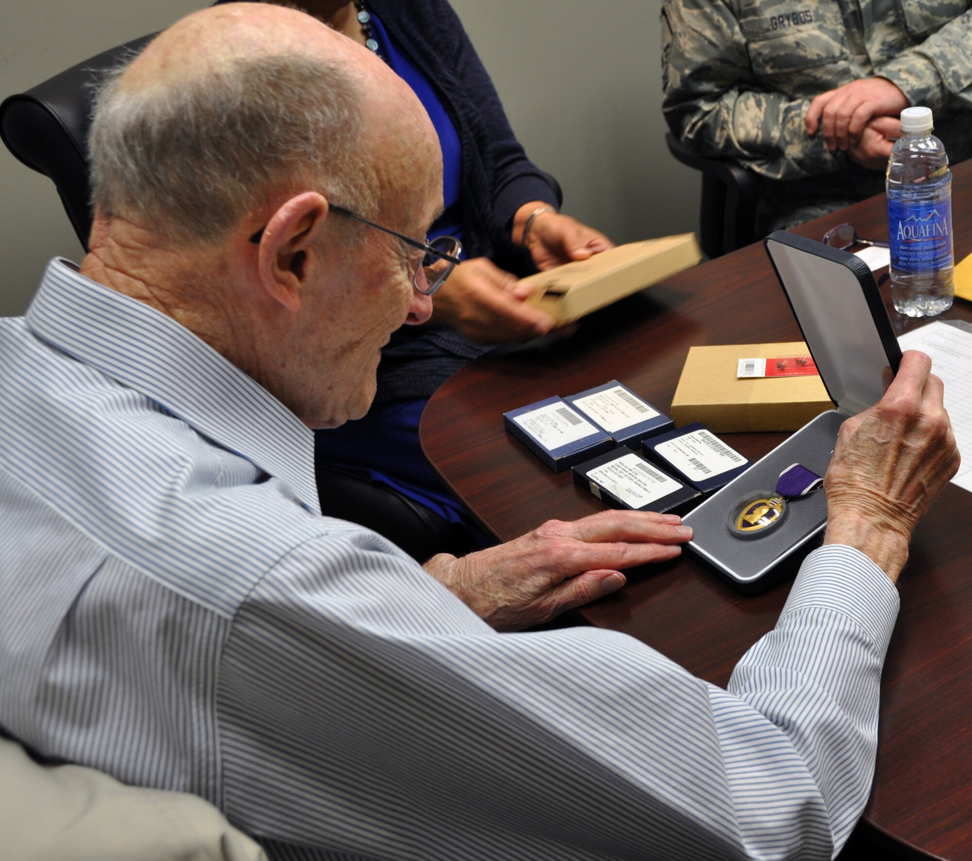 Former 1st Lt. Clayton A. Nattier, a veteran bomber pilot who was held as a prisoner of war during World War II, takes a look at the Purple Heart Medal received from the Air Reserve Personnel Center April 17, 2015, on Buckley Air Force Base, Colo. Nattier visited ARPC to receive his POW Medal among various other medals, then took time to personally meet and thank the members on the recognition service team who assisted him. Members from the ARPC recognition service team who assisted him are: retired Brig. Gen. Pat Quisenberry, evaluations branch chief, Jacqueline Bing, sustainment division chief, Master Sgt. Jeremy Bohn, pre-trained individual manpower division chief, and Master Sgt. Richard Grybos, NCO in charge of training and development. Nattier worked in conjunction with retired Lt. Col. Kathryn Wirkus, a constituent service representative from U.S. representative Ed Perlmutter’s staff, to attain his POW Medal. A formal presentation to award the POW Medal to Nattier is currently being planned by U.S. representative Ed Perlmutter’s office. (U.S. Air Force photo/Tech. Sgt. Rob Hazelett)