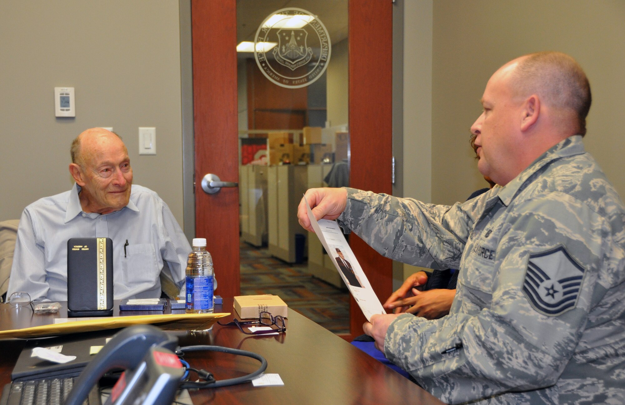 Former 1st Lt. Clayton A. Nattier, a veteran bomber pilot who was held as a prisoner of war during World War II, listens to Master Sgt. Richard Grybos, NCO in charge of training and development, during his visit to the Air Reserve Personnel Center April 17, 2015, on Buckley Air Force Base, Colo. Nattier visited ARPC to receive his POW Medal among various other medals, then took time to personally meet and thank the members on the recognition service team who assisted him. Along with Grybos, other members from the ARPC recognition service team who assisted Nattier are: retired Brig. Gen. Pat Quisenberry, evaluations branch chief, Jacqueline Bing, sustainment division chief, and Master Sgt. Jeremy Bohn, pre-trained individual manpower division chief. Nattier worked in conjunction with retired Lt. Col. Kathryn Wirkus, a constituent service representative from U.S. representative Ed Perlmutter’s staff, to attain his POW Medal. A formal presentation to award the POW Medal to Nattier is currently being planned by U.S. representative Ed Perlmutter’s office. (U.S. Air Force photo/Tech. Sgt. Rob Hazelett)