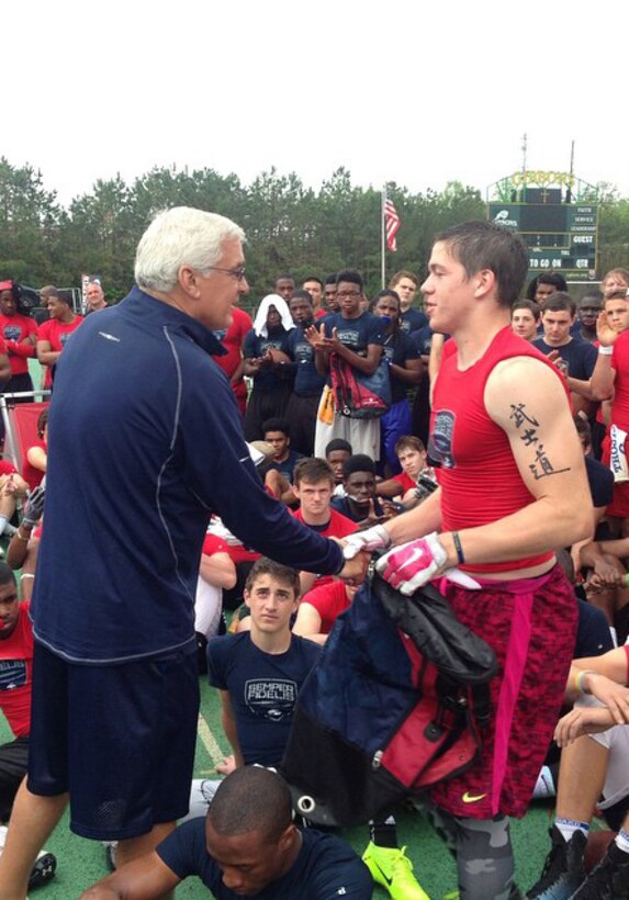 Peter Vaas, the camp director for the Raleigh Semper Fidelis Football Camp, presents the Offensive Player of the Camp award to Tyler Crist, a wide receiver on the Kecoughtan High School football team in Hampton, Virginia, during the camp at Cardinal Gibbons High School in Raleigh, North Carolina, April 19, 2015. The one-day camp brought in close to 200 high school football players from North Carolina and Virginia to give them a chance to work with U.S. Marines and National Football League coaches. The Semper Fidelis Football Camps are taking place in 24 cities across the country to showcase the Marine Corps’ commitment to developing quality citizens and highlight how Marine Corps values of honor, courage and commitment relate to success both on and off the field.  (U.S. Marine Corps photo by Sgt. Dwight A. Henderson/Released) 