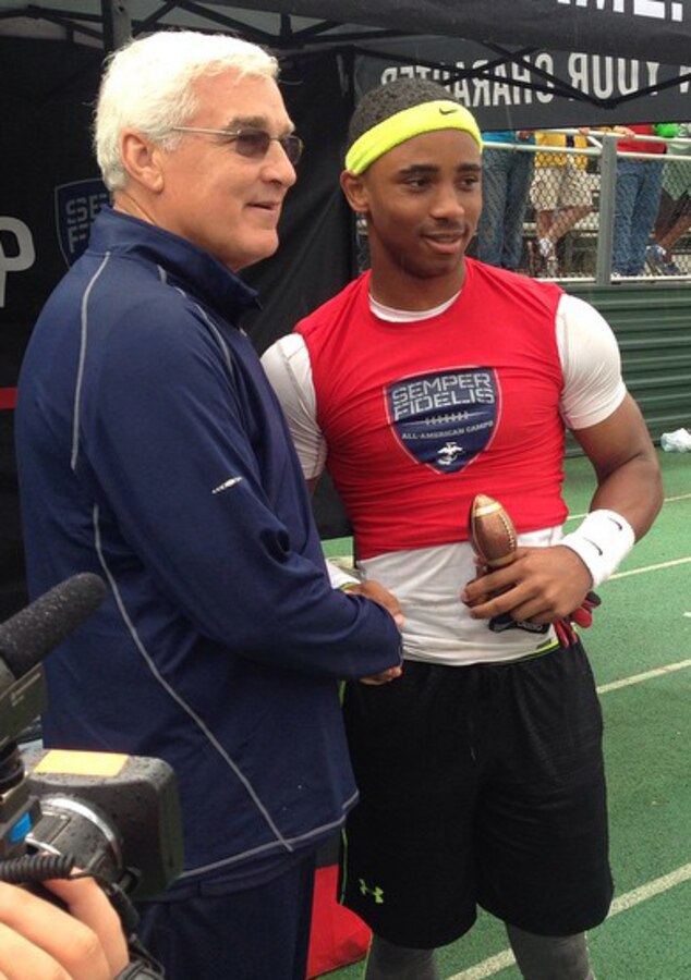 Peter Vaas, the camp director for the Raleigh Semper Fidelis Football Camp, presents the Defensive Player of the Camp award to Timothy Glass, a defensive back on the Liberty Christian Academy High School football team in Lynchburg, Virginia, during the camp at Cardinal Gibbons High School in Raleigh, North Carolina, April 19, 2015. The one-day camp brought in close to 200 high school football players from North Carolina and Virginia to give them a chance to work with U.S. Marines and National Football League coaches. The Semper Fidelis Football Camps are taking place in 24 cities across the country to showcase the Marine Corps’ commitment to developing quality citizens and highlight how Marine Corps values of honor, courage and commitment relate to success both on and off the field.  (U.S. Marine Corps photo by Sgt. Dwight A. Henderson/Released) 