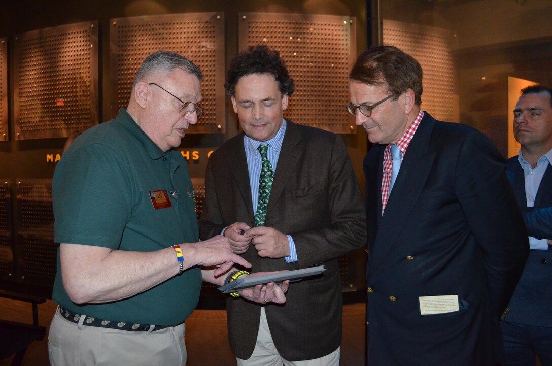 Retired Marine Col. Barry Colassard, a docent at the National Museum of the Marine Corps, presents sand from Iwo Jima and shows pictures of Mount Suribachi to Duke Leopold-Engelbert de Arenberg, center, and Count Bernard de Grunne of Belgium. Arenberg supports Azalea Charities, a veteran and community support organization based in Dumfries, and toured the museum April 15. 