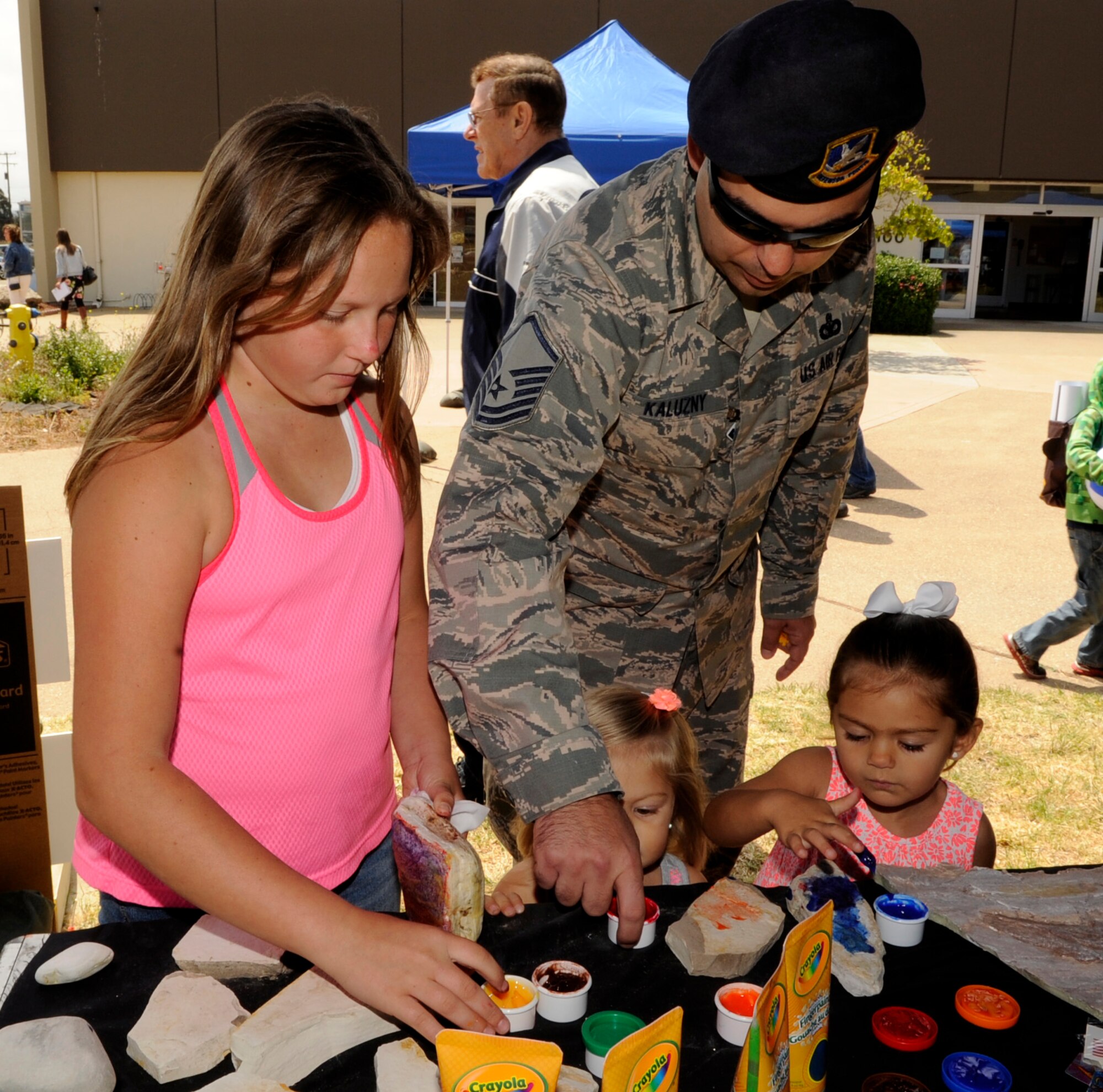 Master Sgt. James Kaluzny, 30th Security Forces Squadron NCOIC of standardization and evaluations, helps his daughters finger paint during an Earth Day celebration, April 22, 2015, Vandenberg Air Force Base, Calif. The event was hosted by members of the 30th Civil Engineer Squadron and aimed to engage members of the base through interactive displays. (U.S. Air Force photo by Senior Airman Shane Phipps/Released)
