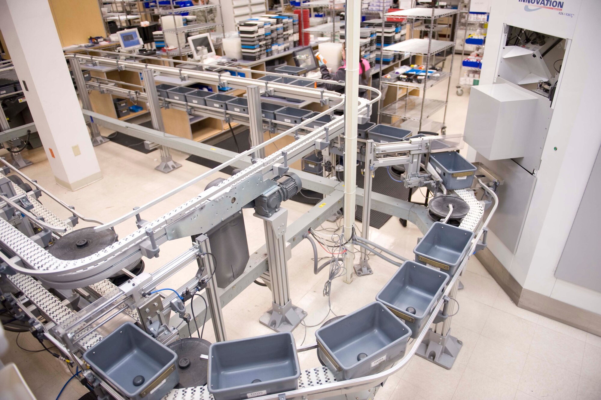 A conveyor belt begins circling manual fill stations at the satellite pharmacy on Nellis Air Force Base, Nev., April 17, 2015. Refills begin at “Robby”, a robotic dispensing system, and a pharmacy staff member will fill medications such as inhalers or creams. Once this step is complete, the conveyor belt will continue to move to a checking station to verify each prescription is filled correctly. (U.S. Air Force photo by Airman 1st Class Rachel Loftis) 