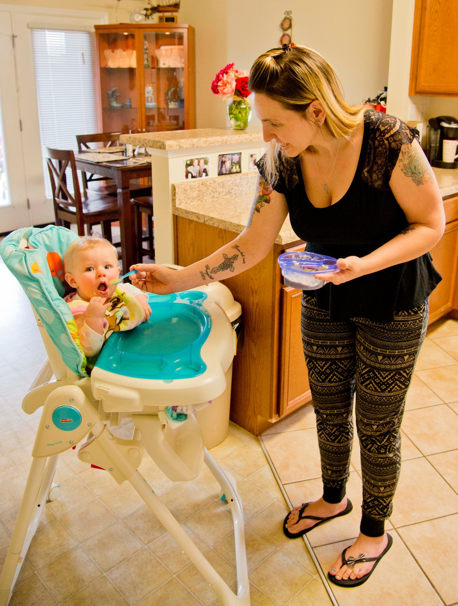 Misty Trask, Travis Air Force Base, Calif., Family Child Care provider, feeds a baby in her home April 22, 2015. FCC is an alternate to the child development centers and provides in-home care for infants to school-age children from one of 18 licensed providers both on and off base. (U.S. Air Force photo/Senior Airman Nicole Leidholm)