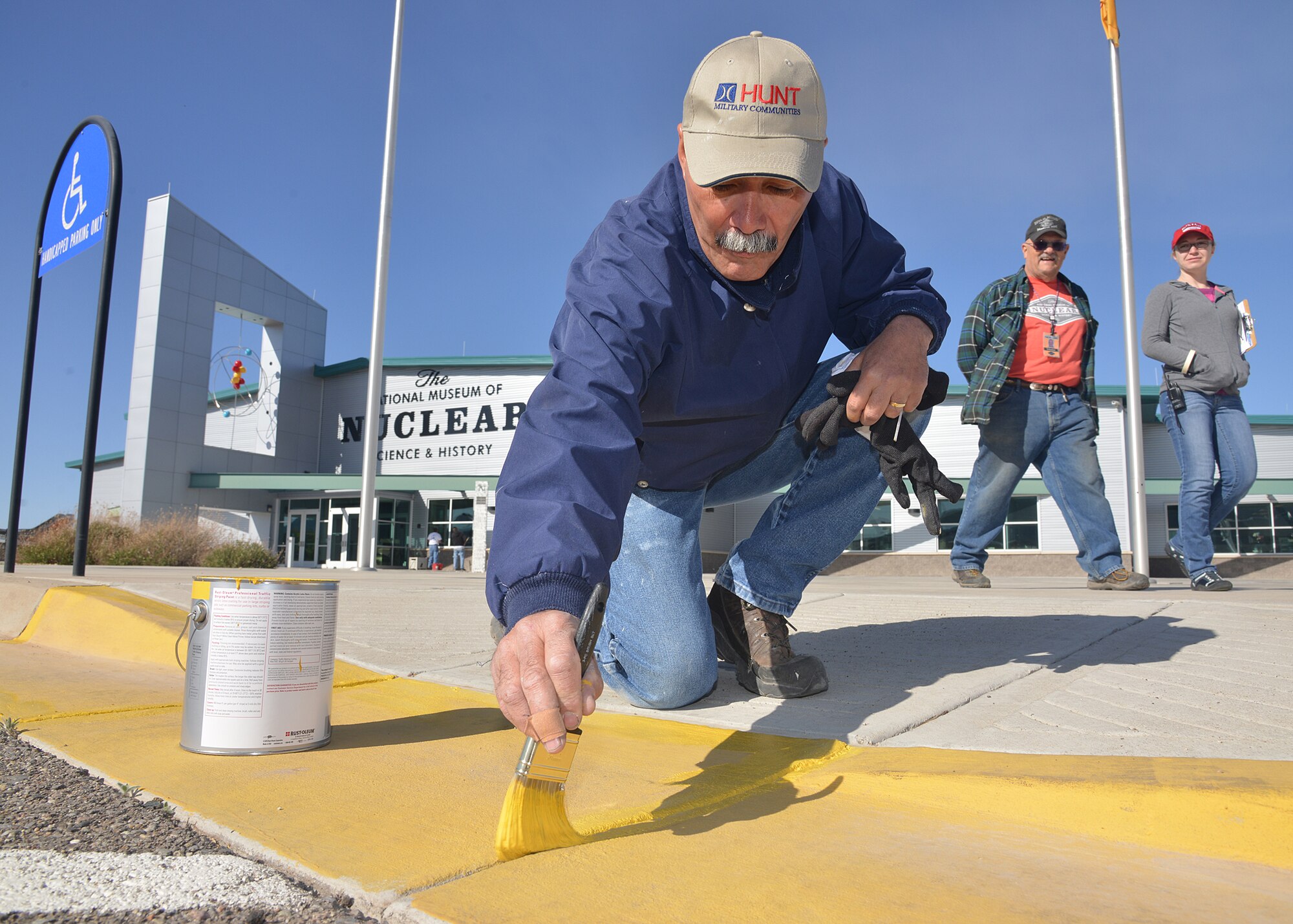 Marco Illescas of base housing puts a final finishes of a curb painting at the National Museum of Nuclear Science and History.Twenty-five volunteers — all associated with Hunt Military Communities — joined a group of museum volunteers to work on tasks like re-painting wheelchair ramps and fire lane curbs, painting the base of the museum’s Mace missile, removing weeds and trash, cleaning flower beds, watering plants and raking rocks. (Photo by Todd Berenger)