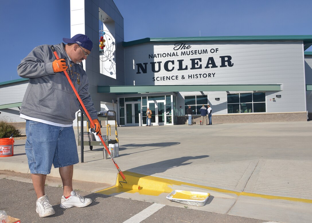 Michael Ulibarri applies new yellow paint for a handicap access ramp at the National Museum of Nuclear Science and History.Twenty-five volunteers — all associated with Hunt Military Communities — joined a group of museum volunteers to work on tasks like re-painting wheelchair ramps and fire lane curbs, painting the base of the museum’s Mace missile, removing weeds and trash, cleaning flower beds, watering plants and raking rocks. (Photo by Todd Berenger)