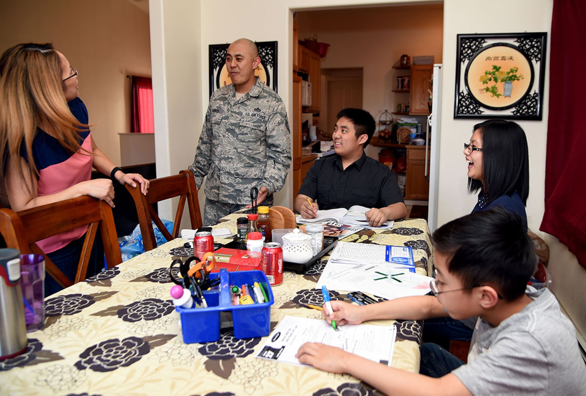 Air Force Master Sgt. Tony Andres playfully interacts with his wife, Liezl while their children (clockwise) Devin, 16 and Malia 12, laugh at them, and Keoni, 8, does his homework at their home in Anchorage. Despite multiple moves, deployments and temporary duty locations, the family tries to keep a balance of a normal life. There are approximately 1.9 million U.S. military children worldwide who face unique challenges related to military life and culture. (U.S. Air Force photo/Staff Sgt. Sheila deVera)