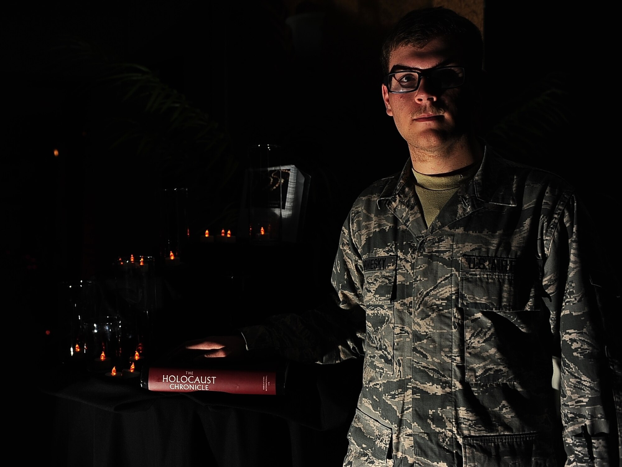 Airman 1st Class Sean Juroviesky, member of the Holocaust Remembrance Committee, poses for a photo near a Holocaust Days of Remembrance light display April 21 at the Columbus Club on Columbus Air Force Base, Mississippi. The committee put together a museum featuring a video on the Holocaust and a room full of informational boards and props. (U.S. Air Force photo/Airman Daniel Lile)