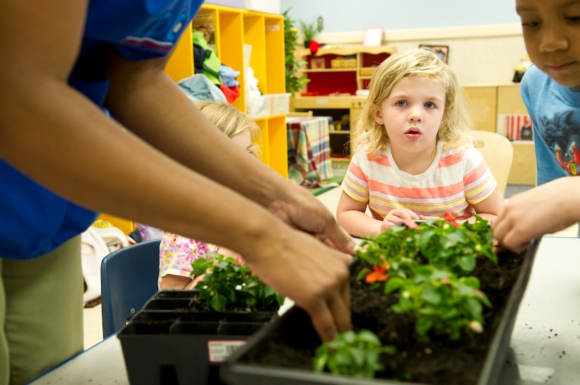 A child watches her classmates as they repot flowers at the Child Development Center II at Joint Base Andrews, Md., for Earth Day, April 22, 2015. The children repotted pansies and marigolds inside, with plans to plant sunflower seeds outside in the near future. (U.S. Air Force photo/Senior Airman Mariah Haddenham)

