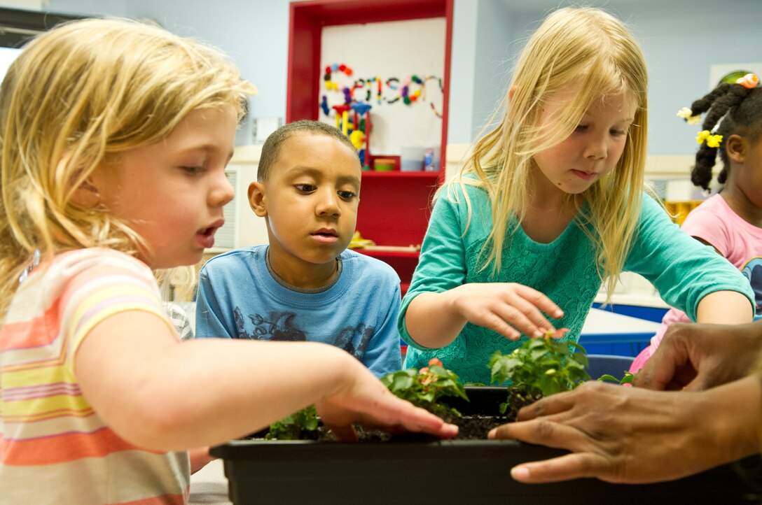 Children help each other repot flowers at the Child Development Center II at Joint Base Andrews, Md., for Earth Day, April 22, 2015. The children repotted the flowers with their teachers to learn more about plants and how they grow. (U.S. Air Force photo/Senior Airman Mariah Haddenham)