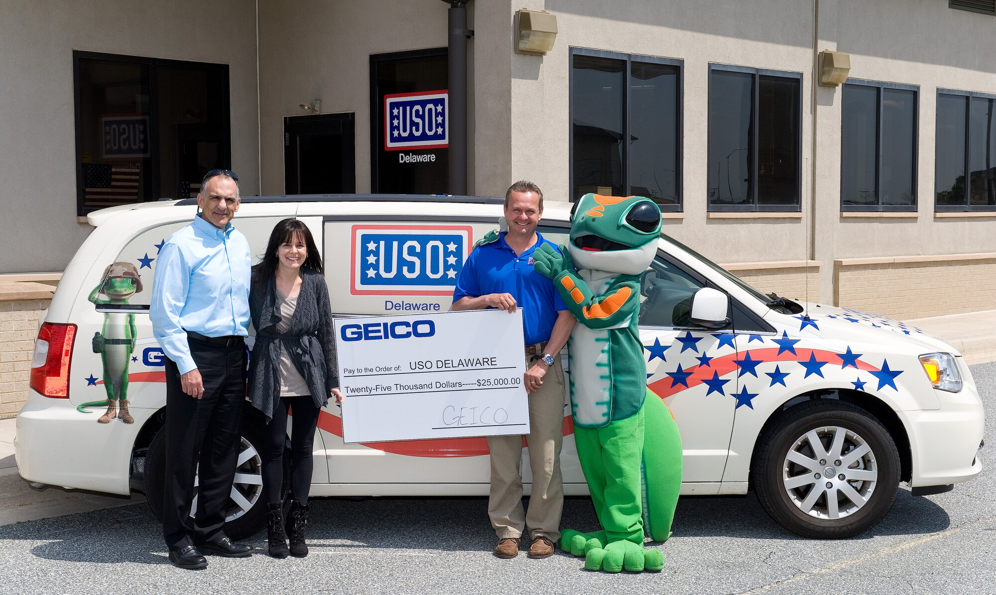 Anne Scharp, GEICO field representative for Delaware, second from the left, presents a $25,000 donation to Bruce Kmiec, United Service Organizations Delaware center director, second from right, April 22, 2015, at the USO Delaware Community Center on Dover Air Force Base, Del. Kmiec accepted the GEICO corporate donation on behalf of USO Delaware which will be used to support programs and services for service men, women and their families.  Also pictured are Mike Tatoian, USO Delaware Advisory Council chairman, left, and the GEICO Gecko, Terri Hansen, USO Delaware volunteer, right. (U.S.  Air Force photo/Roland Balik)