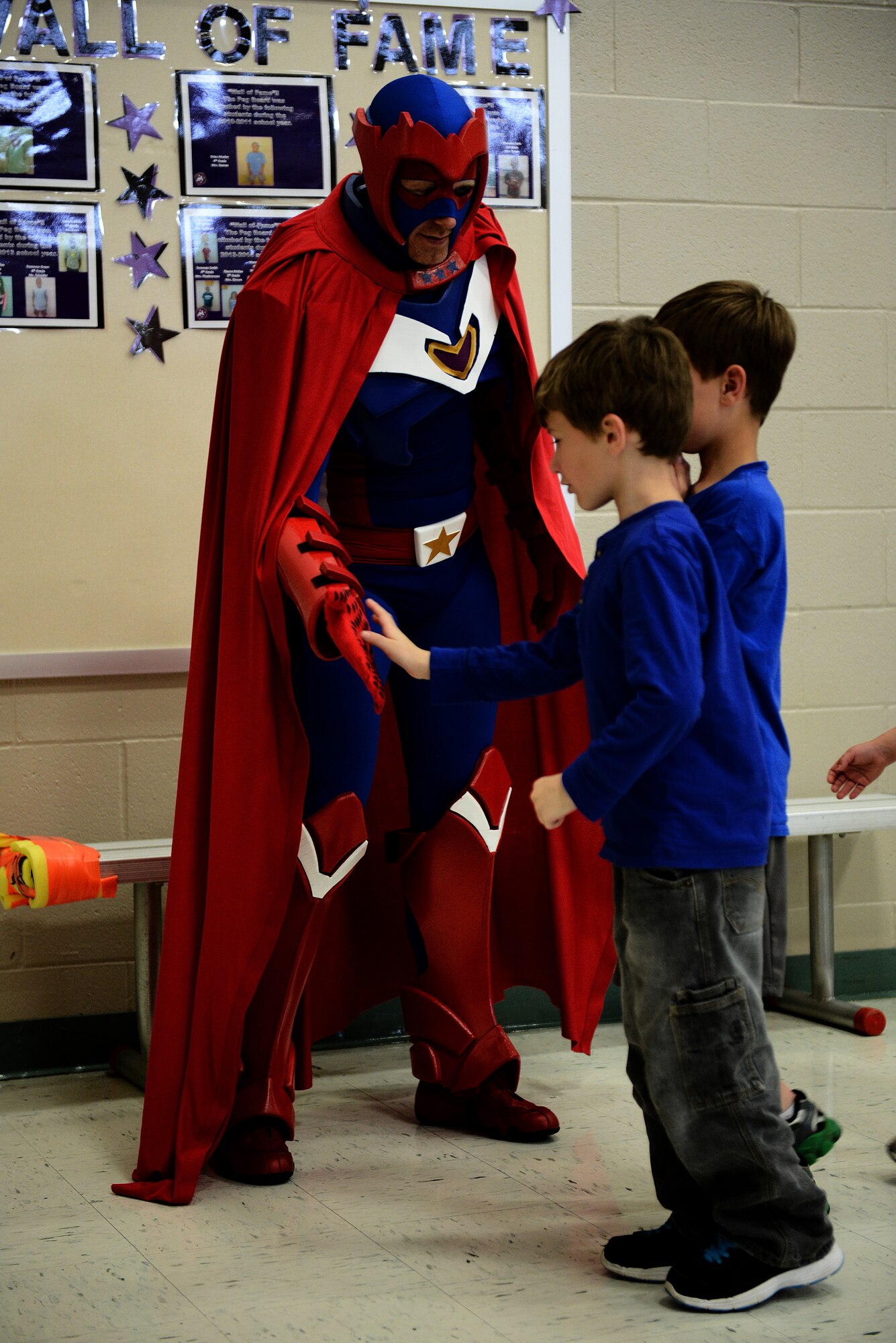 Captain Freedom, a military based superhero, gives the children of Scott Elementary high-fives as they leave the gym April 17, 2015, at Scott Air Force Base, Illinois. The event was used to launch the beginning of the Heroes to Heros program, which exists solely to help children understand deployments.(U.S. Air Force photo/Senior Airman Jake Eckhardt)