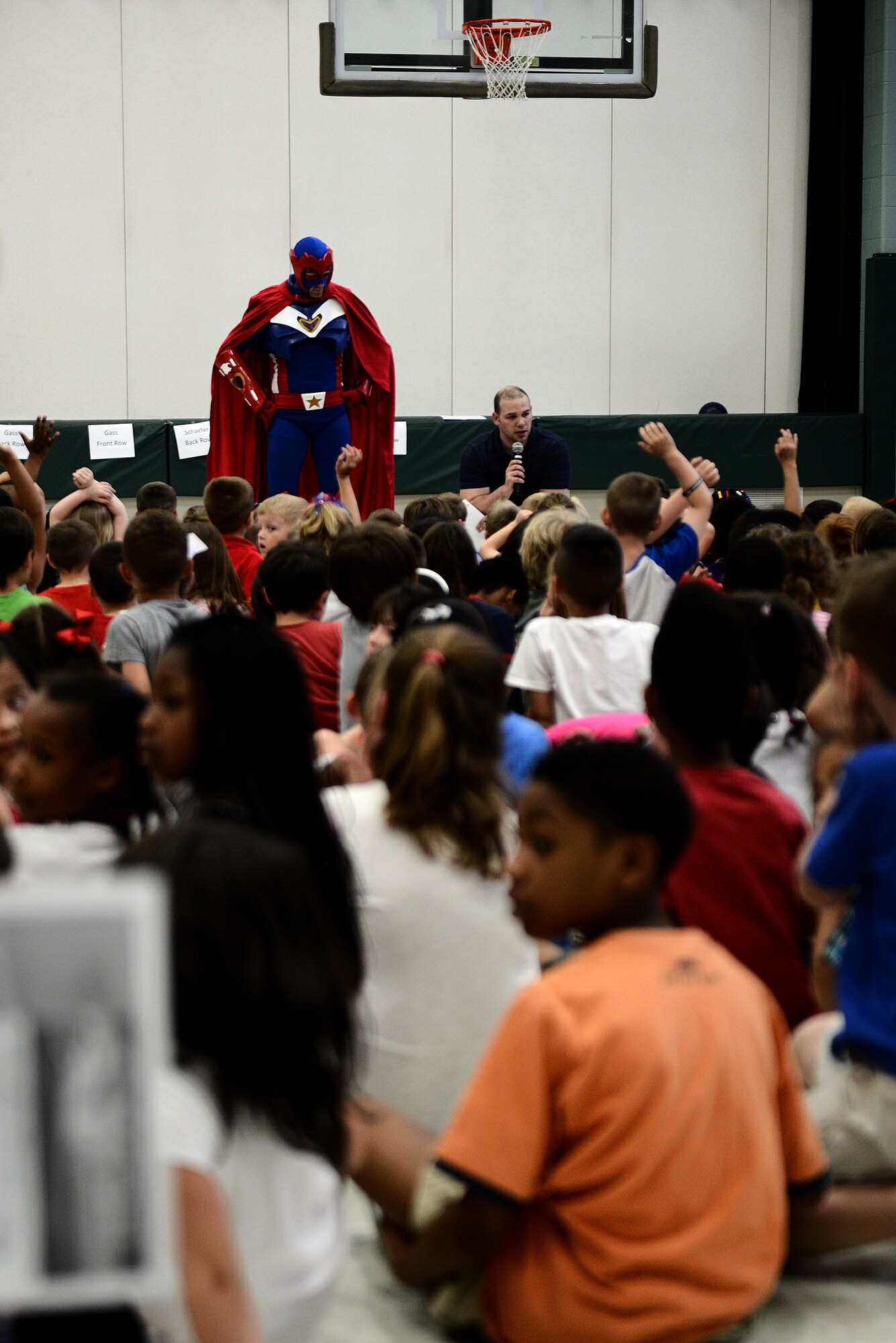 Captain Freedom, a military based superhero, and Tech. Sgt. Trenton Seibel, creator of Captain Freedom and the Heroes to Heroes program, ask the children of the Scott Elementory School questions about deployments April 17, 2015, at Scott Air Force Base, Illinois. The superhero explained why deployments are necessary and how the children can help while their parent or parents are away from home.(U.S. Air Force photo/Senior Airman Jake Eckhardt)