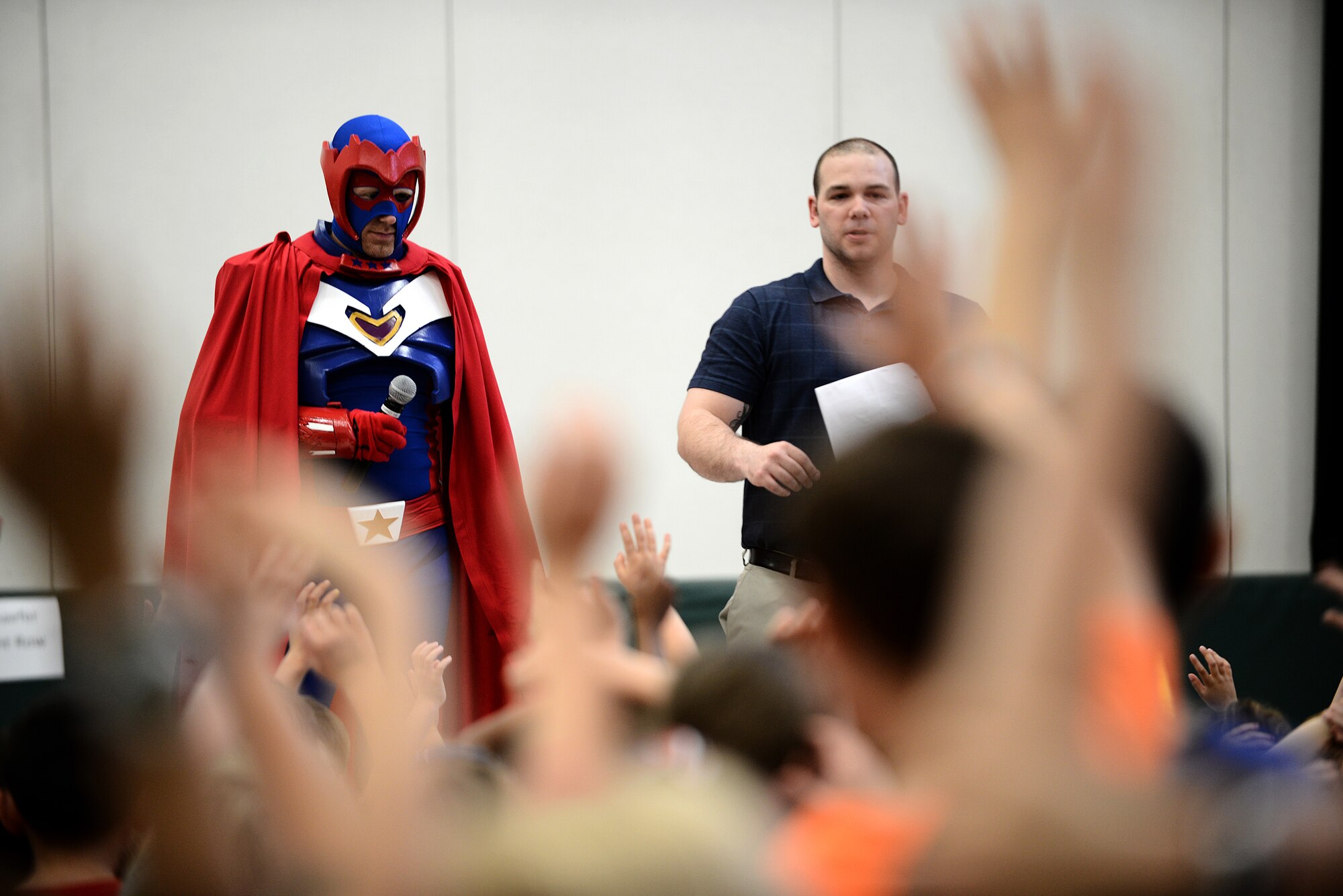 Captain Freedom, a military based superhero, and Tech. Sgt. Trenton Seibel, creator of Captain Freedom and the Heroes to Heroes program, ask the children of the Scott Elementory School questions about deployments April 17, 2015, at Scott Air Force Base, Illinois. The superhero explained why deployments are necessary and how the children can help while their parent or parents are away from home.(U.S. Air Force photo/Senior Airman Jake Eckhardt)