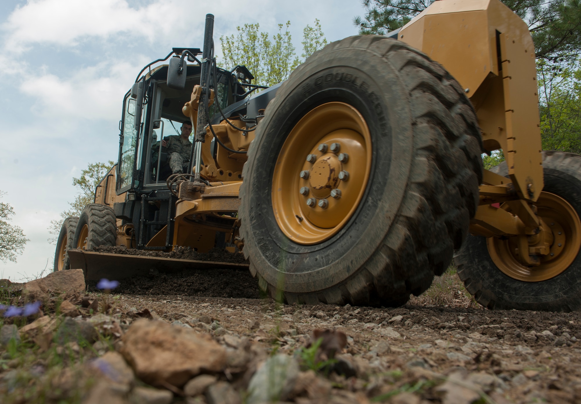Senior Airman Stephen DenBleyker, a 19th Civil Engineer Squadron pavements and construction equipment journeyman, uses a grader to level out an unpaved road April 8, 2015, at Little Rock Air Force Base, Ark. One of their many responibilities is to maintain more than 25 miles of roads located on base. (U.S. Air Force photo by Airman 1st Class Scott Poe)