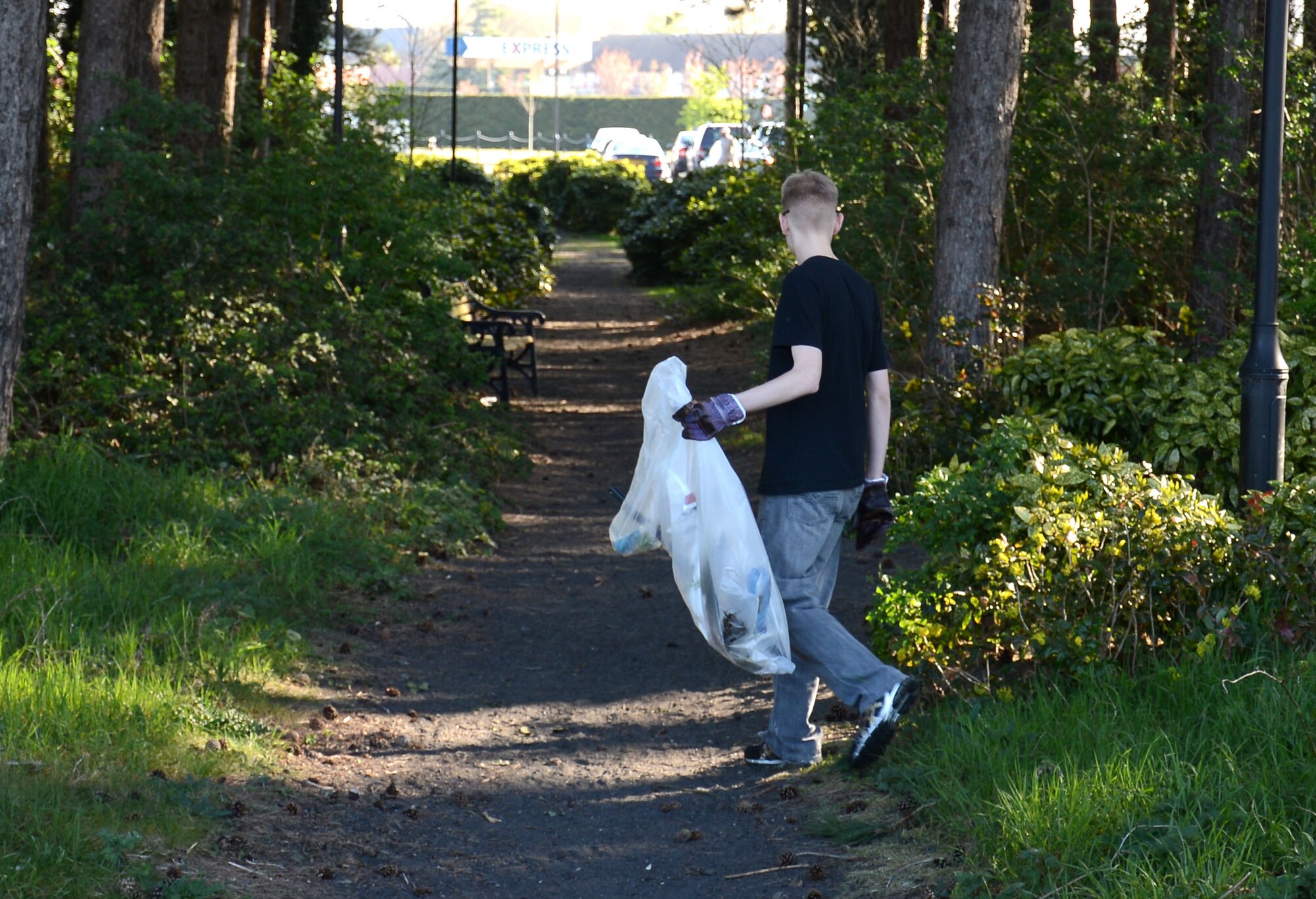 U.S. Air Force Airman 1st Class Lance Theewen, 100th Security Forces Squadron response force member from David City, Neb., walks along the woods behind Heritage Park to look for trash April 21, 2015, on RAF Mildenhall, England. Airmen collected trash between Heritage Park and the BXtra as part of one of the earth week activities held on base. (U.S. Air Force photo by Gina Randall/Released)