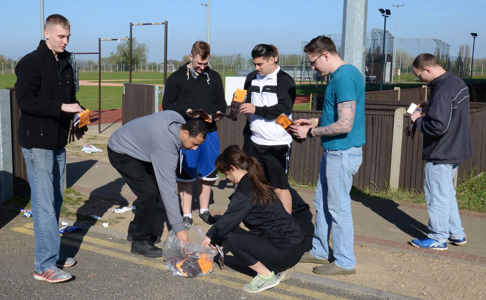 Members from the 100th Security Forces Squadron put on protective gloves prior to a cleanup around Heritage Park April 21, 2015, on RAF Mildenhall, England. The participants were given gloves to wear to protect them from sharp plants and potential contaminated objects. (U.S. Air Force photo by Gina Randall/Released)