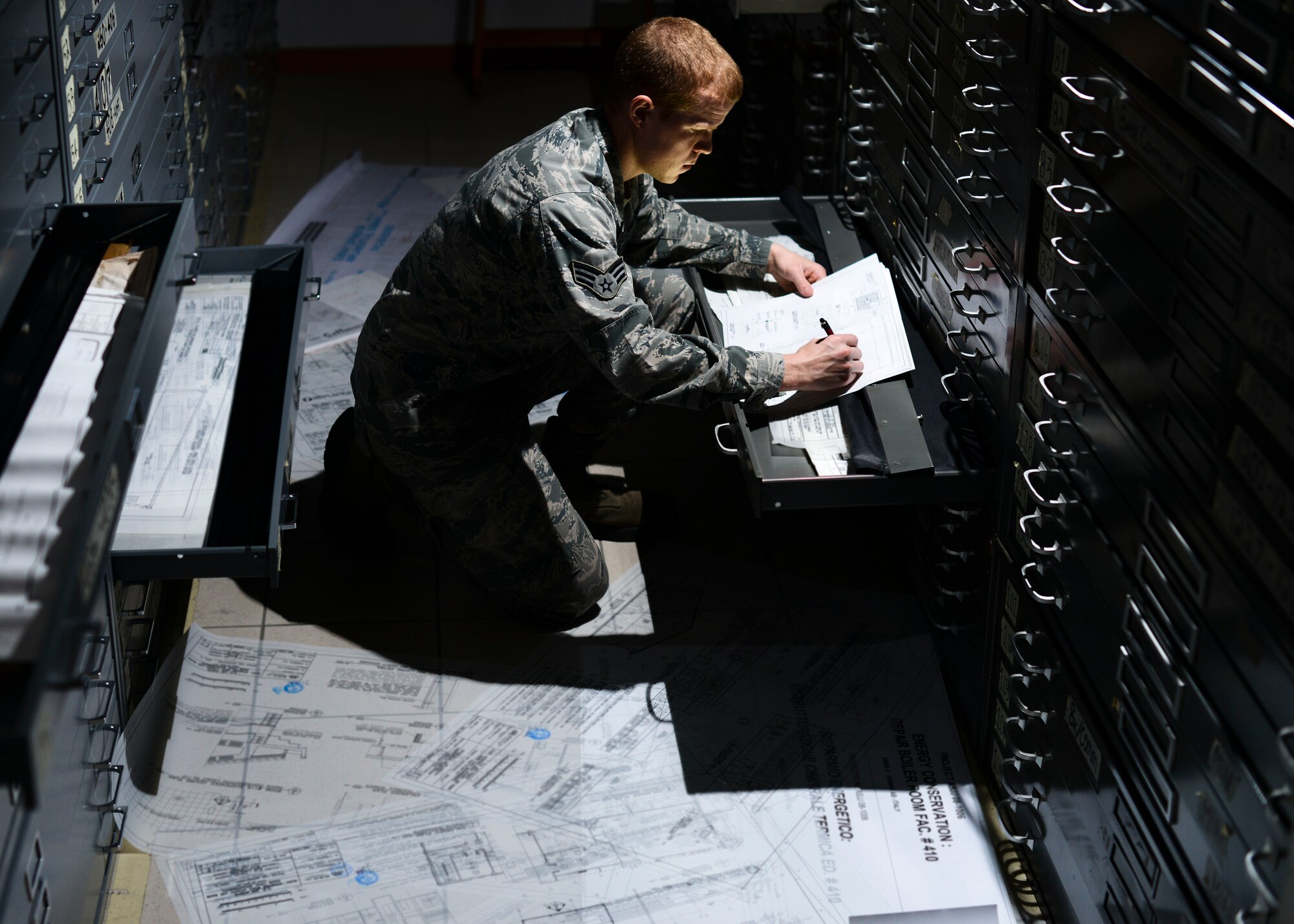 U.S. Air Force Senior Airman Todd Hall, 31st Civil Engineer Squadron engineering technician, looks through a drawing vault to locate building utility plans, April 17, 2015, at Aviano Air Base, Italy. Hall maintains a physical and digital database of Aviano’s maps, which include building floorplans, future projects, restructuring plans and more. (U.S. Air Force photo by Senior Airman Austin Harvill/Released)