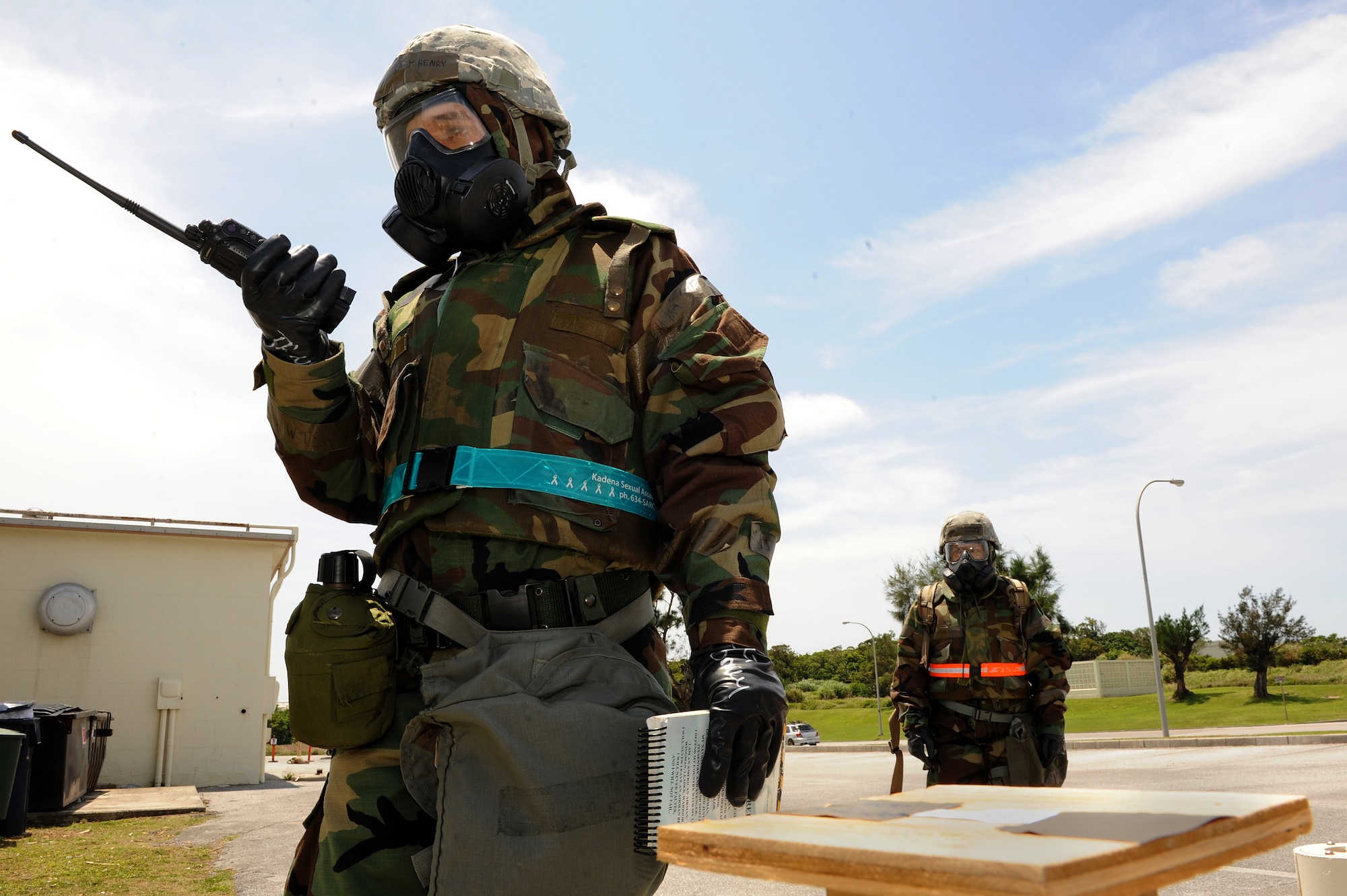 U.S. Air Force Airman 1st Class Zackary Henry, 18th Wing Public Affairs photojournalist, reports his findings through hand-held radio during a simulated post-attack reconnaissance sweep on Kadena Air Base, Japan, April 23, 2015. During a PAR sweep, Airmen check several strips of chemically reactive paper placed on stands around their area of responsibility in order to determine whether or not their facility has been contaminated by chemical weapons. (U.S. Air Force photo by Airman 1st Class Zade C. Vadnais)