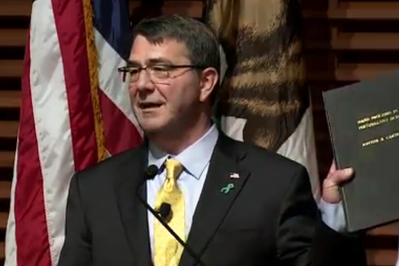 Defense Secretary Ash Carter holds up a copy of his doctoral thesis as he delivers a lecture titled "Rewiring the Pentagon: Charting a New Path on Innovation and Cybersecurity," at Stanford University in Stanford, California, April 23, 2015. The lecture highlighted the Pentagon's new cyber strategy and innovation initiatives. DoD screen shot