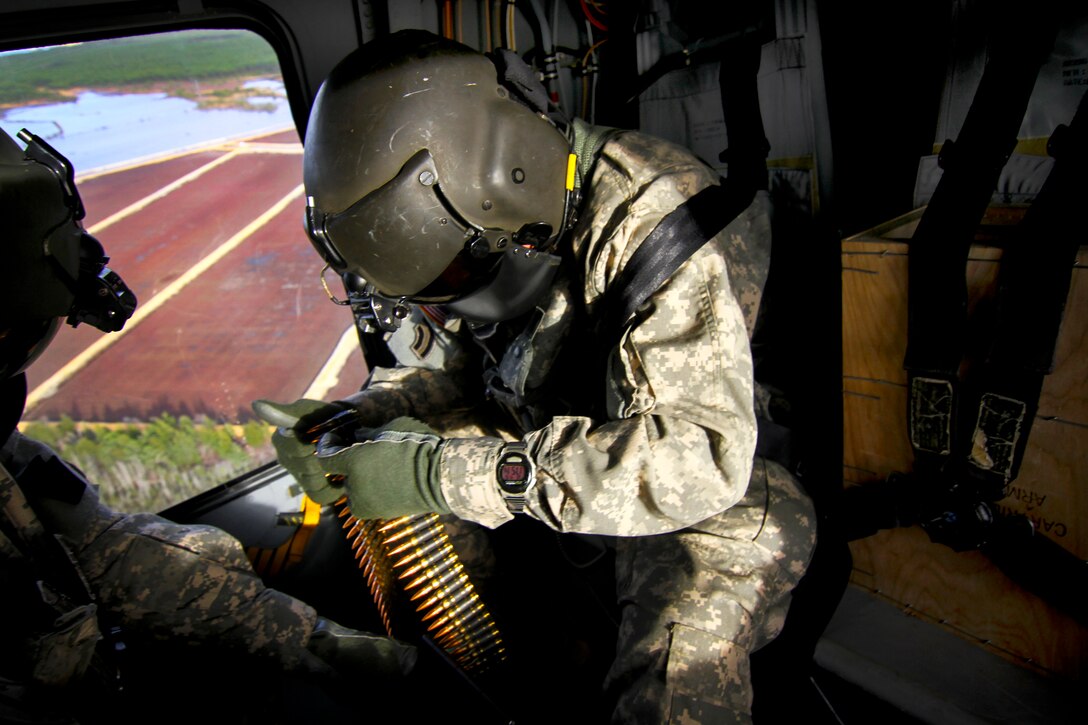 New Jersey Army National Guard helicopter crew chiefs assigned to the 1st Battalion, 150th Aviation Regiment reload 7.62 mm ammunition canisters over Warren Grove Gunnery Range, N.J., April 16, 2015.
