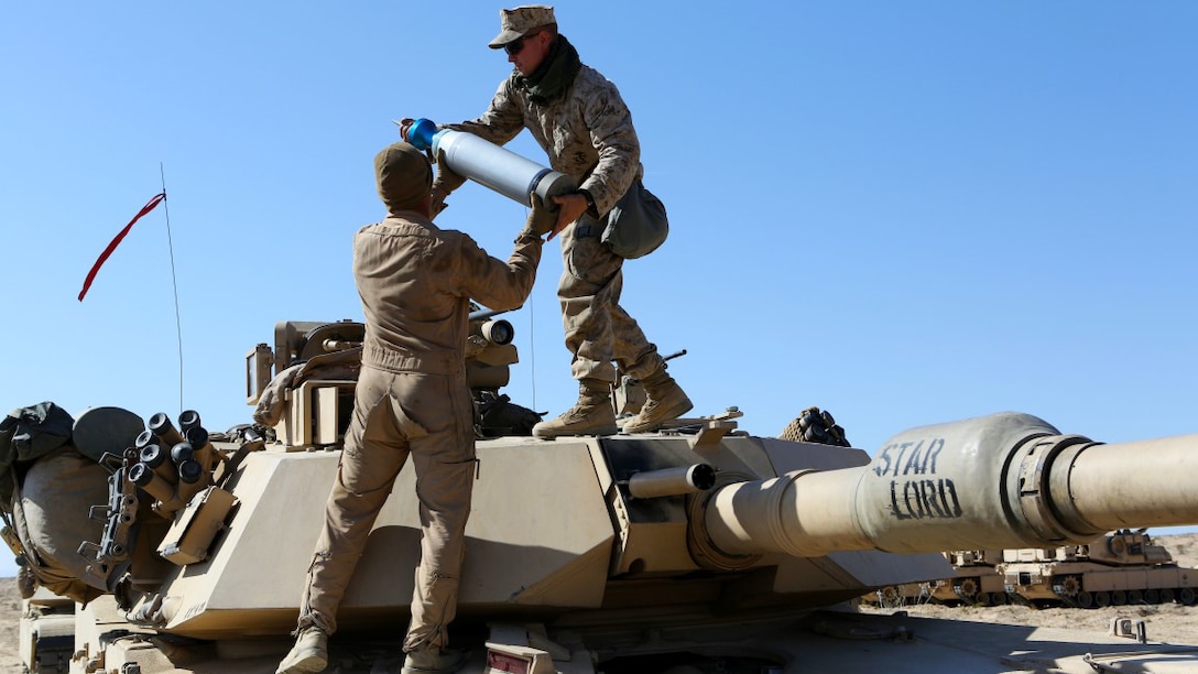 Corporal Christian Bills, gunner, Company A, 1st Tank Battalion, 1st Marine Division, nicknamed “America’s Company,” hands a main gun round to Cpl. Jeffrey Buttler, tank mechanic, Co. A, during Exercise Desert Scimitar aboard Marine Corps Air Ground Combat Center Twentynine Palms, California, April 10, 2015. The training gave the Marines the opportunity to refine and rehearse essential combat skills needed in a battlefield environment. Desert Scimitar is an annual exercise that includes elements from the I Marine Expeditionary Force. The exercise focused on conventional operations and provided realistic training that prepared Marines for overseas operations. (U.S. Marine Corps photo by Sgt. Christopher J. Moore/Released)