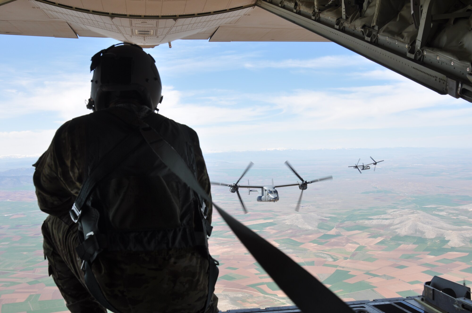 A U.S. Air Force aircraft loadmaster watches two CV-22B Osprey aircraft approach the MC-130J Commando II for refueling April 6, 2015, while flying over Konya, Turkey. The 352nd Special Operations Wing out of RAF Mildenhall, England, provided these aircraft to participate in ISIK, a Turkish armed forces-hosted combat search and rescue event. The other participating nations in ISIK contributed a total of 26 rotary-wing and fixed-wing aircraft for the event. (U.S. Air Force photo by Capt. Laura Balch)