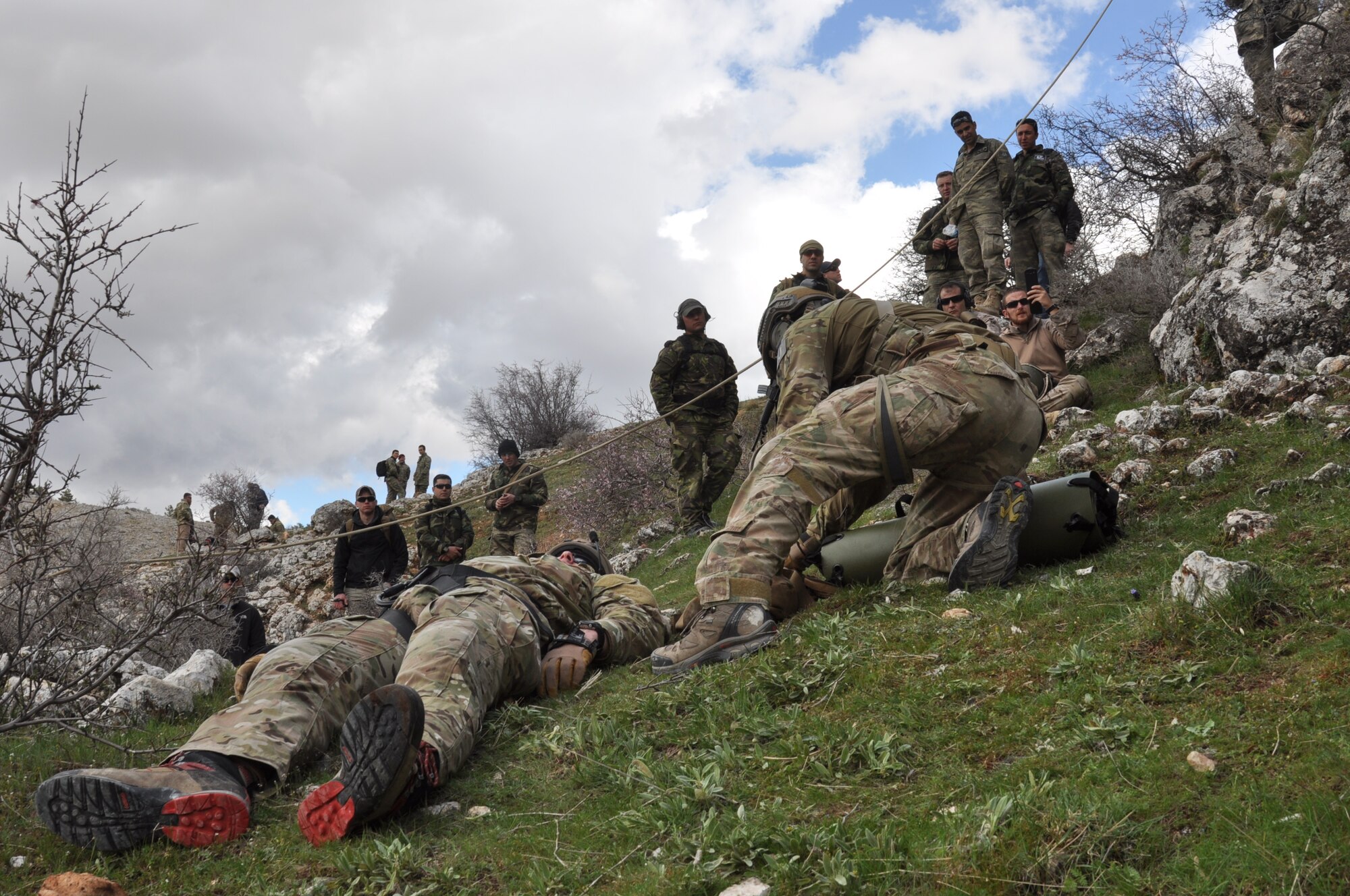 A U.S. Air Force pararescueman, front right, begins preparing a SKEDCO litter for his patient while observers look on April 7, 2015, during ISIK, an international combat search and rescue event, in Konya, Turkey.  Other participants in ISIK observed the pararescueman's procedures to rescue his patient, a simulated downed pilot. (U.S. Air Force photo by Capt. Laura Balch)