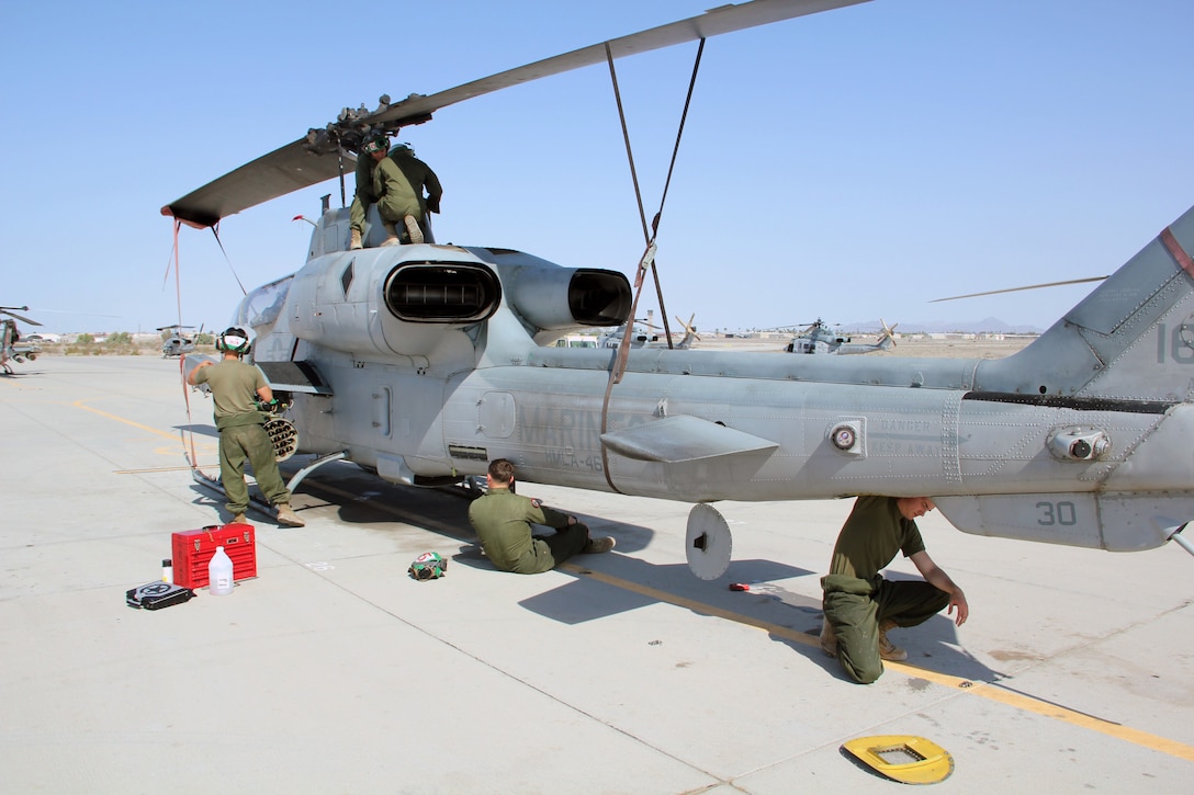 Aircraft mechanic Marines with Marine Aviation Weapons and Tactics Squadron 1 inspect an AH-1W Super Cobra helicopter during a routine maintenance inspection during Weapons and Tactics Instructor course 2-15 aboard Marine Corps Air Station Yuma, Arizona, April 22, 2015. The maintenance that they provide ensures all pilot candidates complete every mission safely. WTI is a seven-week course hosted by MAWTS-1 that provides advanced tactical training to certify Marine pilots as weapons and tactics instructors, preparing them to return to the fleet and serve in key training officer billets. (U.S. Marine Corps photo by Sgt. Cody Haas)