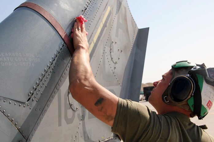 An aircraft mechanic Marine with Marine Aviation Weapons and Tactics Squadron 1 wipes down the tail of an AH-1W Super Cobra helicopter during a routine maintenance inspection during Weapons and Tactics Instructor course 2-15 aboard Marine Corps Air Station Yuma, Arizona, April 22, 2015. The maintenance that they provide ensures all pilot candidates complete every mission safely. WTI is a seven-week course hosted by MAWTS-1 that provides advanced tactical training to certify Marine pilots as weapons and tactics instructors, preparing them to return to the fleet and serve in key training officer billets. (U.S. Marine Corps photo by Sgt. Cody Haas)