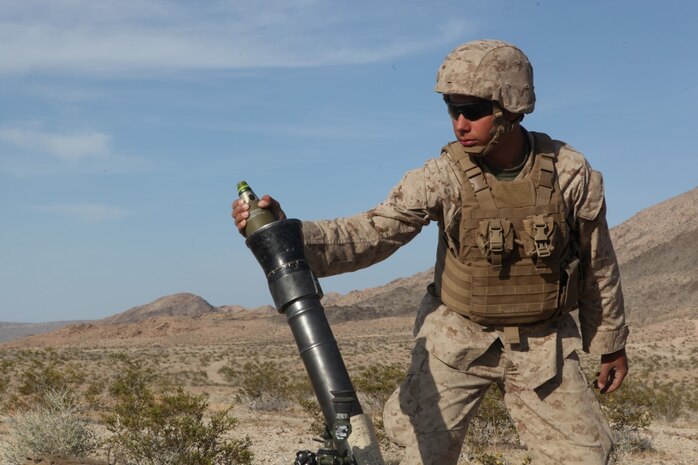 PFC Michael Ainsworth, a mortarman with Weapons Company, 3rd Battalion, 5th Marine Regiment, prepares to drop a mortar round during a combined-arms raid at Army National Training Center Fort Irwin, April 11, 2015. The raid was conducted by 1st Light Armored Reconnaissance Battalion as part of exercise Desert Scimitar 2015.