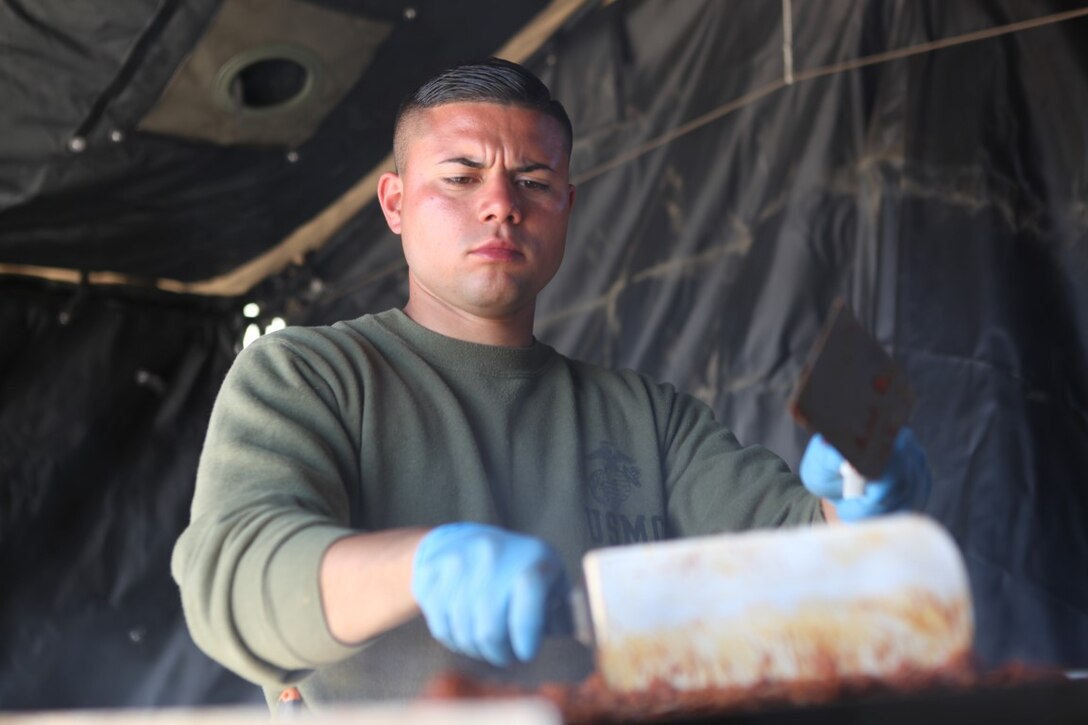 Sgt.  Arturo Torres, a food service specialist with 1st Light Armored Reconnaissance Battalion, 1st Marine Division, I Marine Expeditionary Force, prepares evening chow for Marines participating in Exercise Desert Scimitar at Army National Training Center Fort Irwin, April 9, 2015. Torres, who was a personal cook for a general, attended culinary schools in New York and San Francisco and uses the skills he learned to make field rations more appealing to Marines.