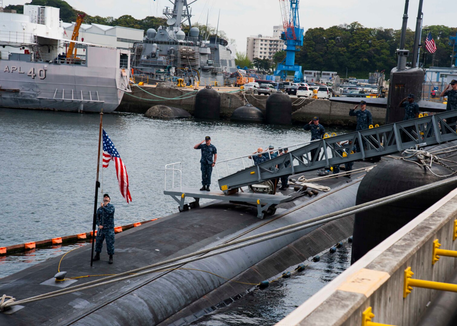 FLEET ACTIVITIES YOKOSUKA, Japan (April 22, 2015) The American flag is raised aboard the Los Angeles-class attack submarine USS Oklahoma City (SSN 723) as crewmembers render honors. Oklahoma City is moored at Fleet Activities Yokosuka during a scheduled port visit as part of its deployment to the western Pacific. 
