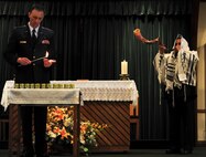 Master Sgt. Michael Felan, 1st Special Operations Civil Engineer Squadron NCO in charge of heavy equipment, plays the Shofar, while Chaplain Mark Hunsinger lights candles, during the Holocaust memorial service at the base chapel on Hurlburt Field Fla., April 22, 2015. The memorial was held as a remembrance to honor those who lost their lives during the Holocaust. (U.S. Air Force photo by Senior Airman Meagan Schutter)