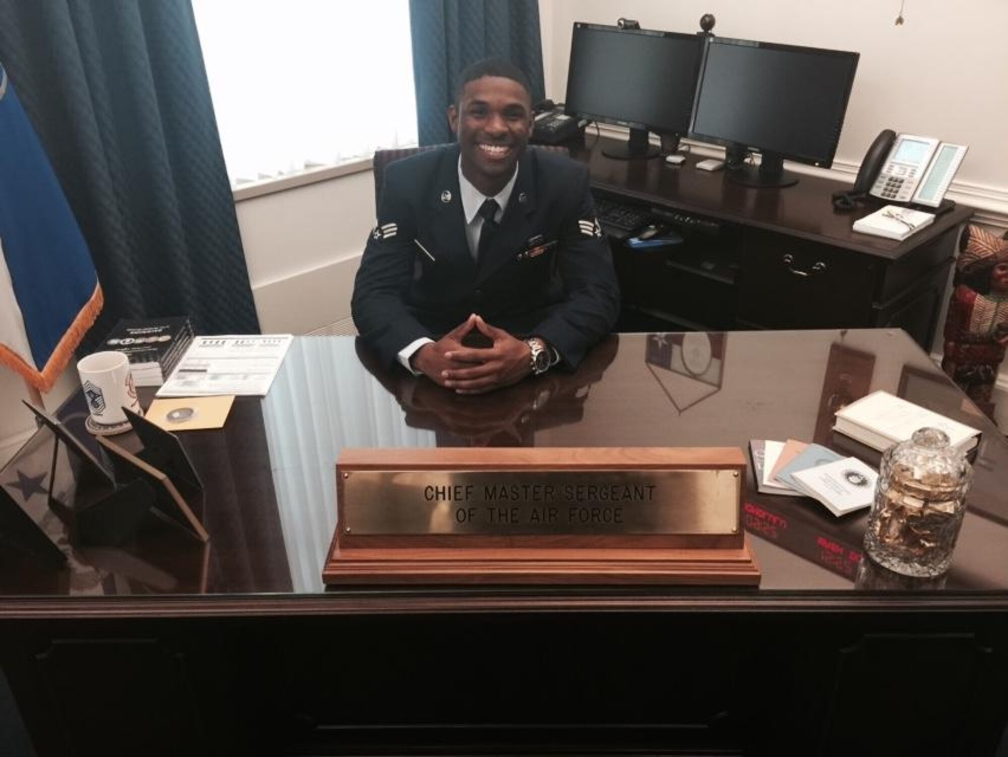 Senior Airman Matthews, 9th Aircraft Maintenance Squadron U-2 assistant dedicated crew chief, poses for a picture behind the desk of Chief Master Sgt. of the Air Force James A. Cody in Washington D.C., April 16, 2015. (Courtesy photo)